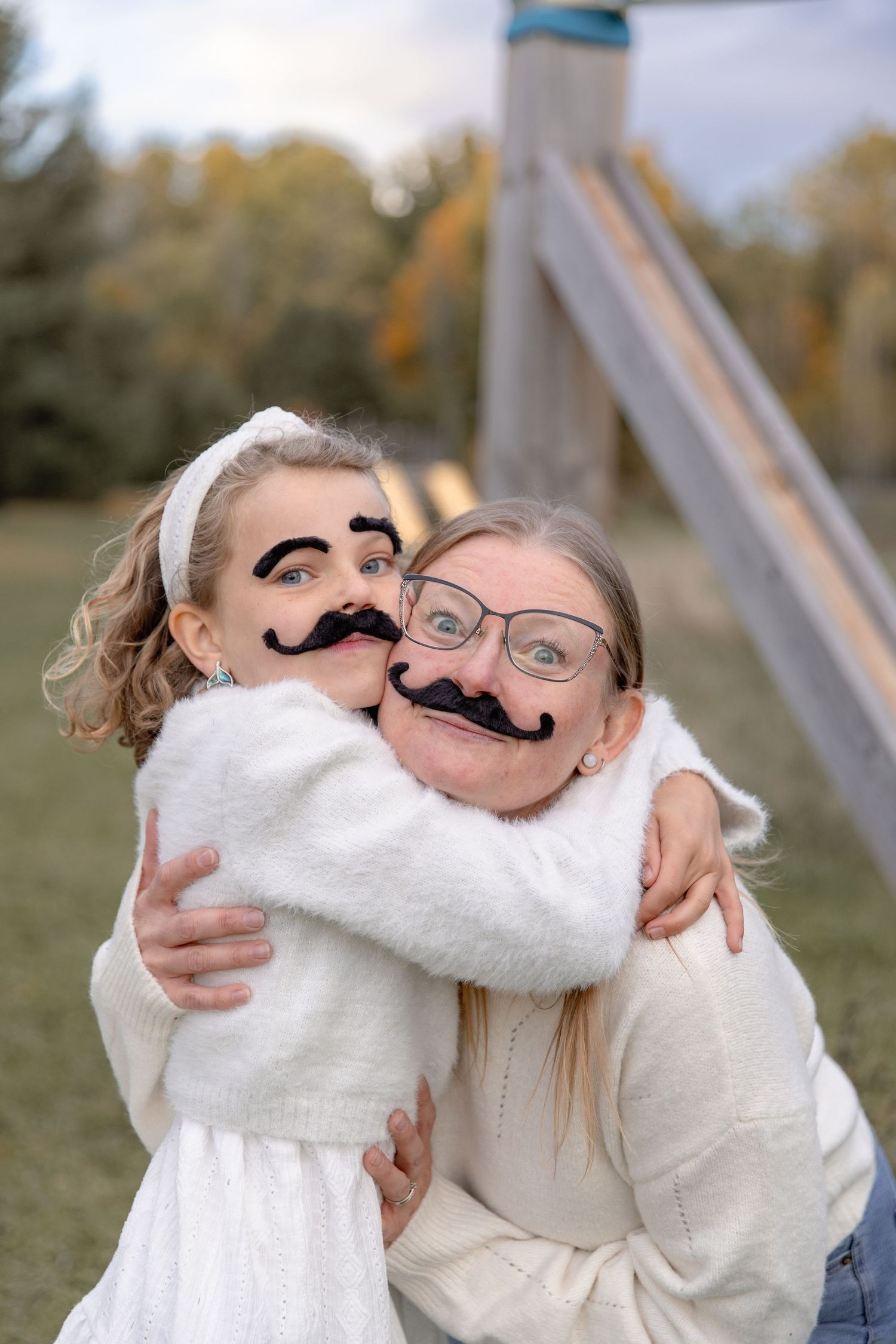 A series of photos showing playful moments with people wearing fake mustaches and white sweaters outdoors in autumn.