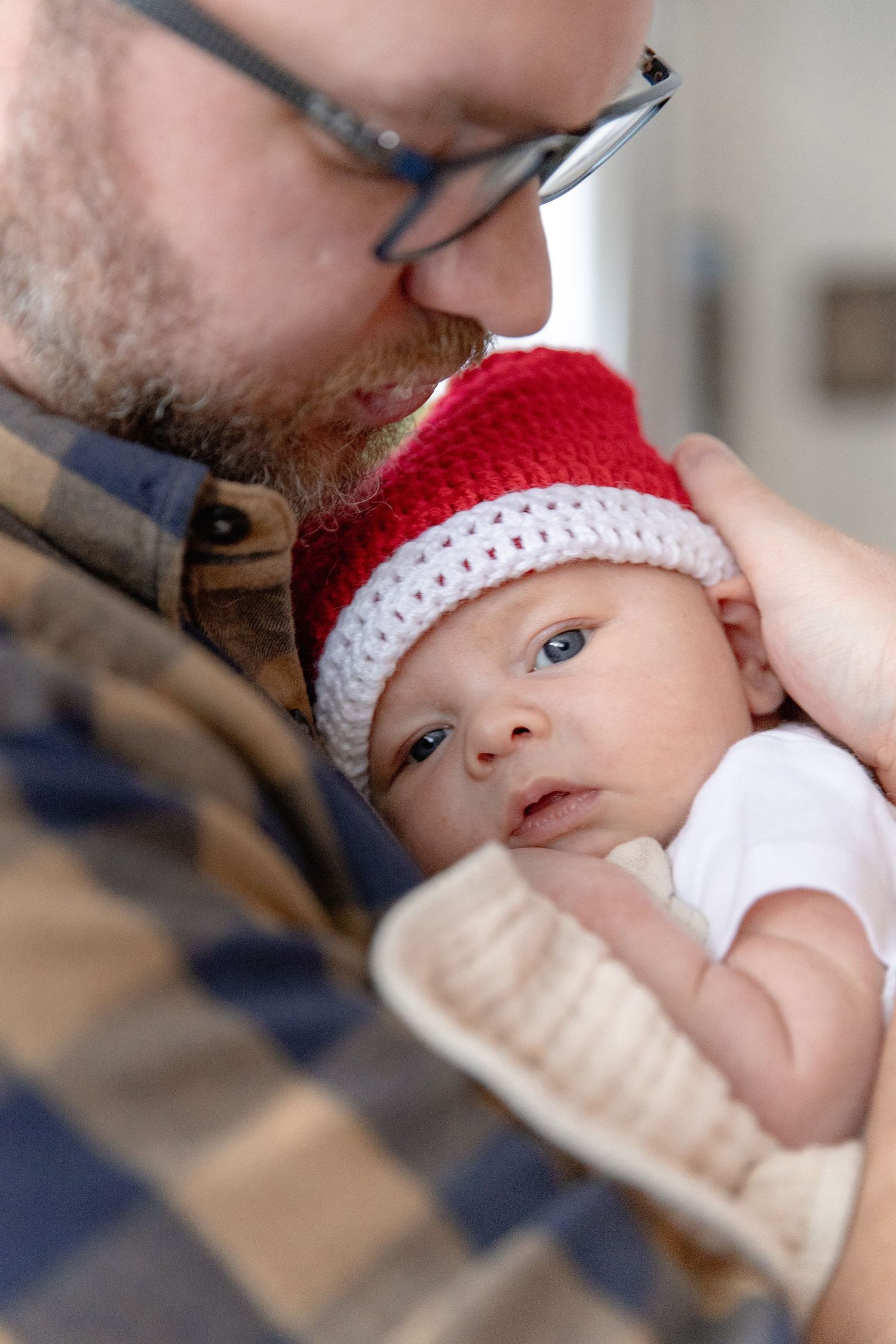 A baby wearing a red and white crocheted hat rests in a caregiver's arms in a series of tender moments.