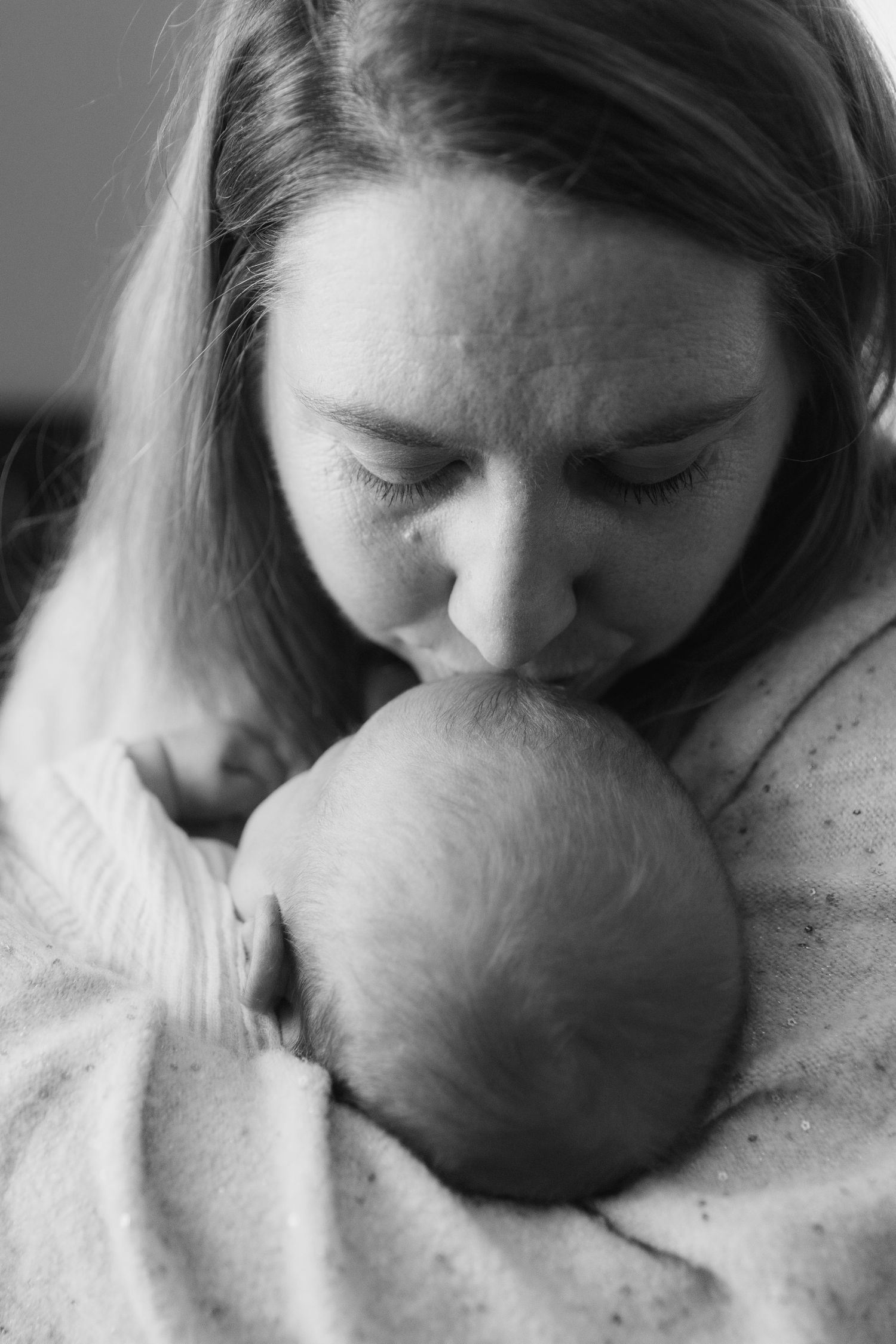 A tender black and white photo sequence showing a person gently kissing and nuzzling a newborn baby.