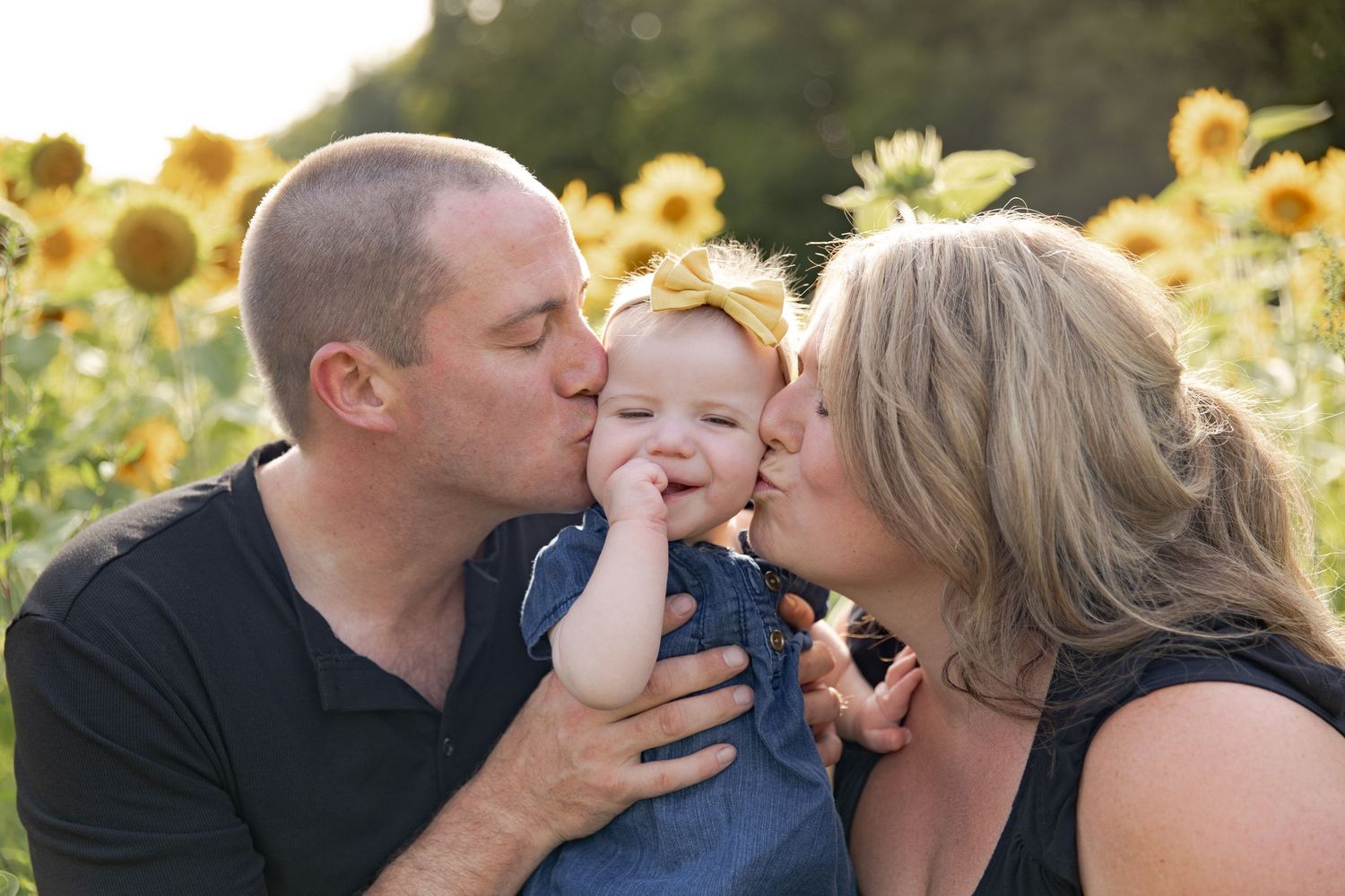 Family poses together in sunflower field during golden hour for outdoor portrait session.