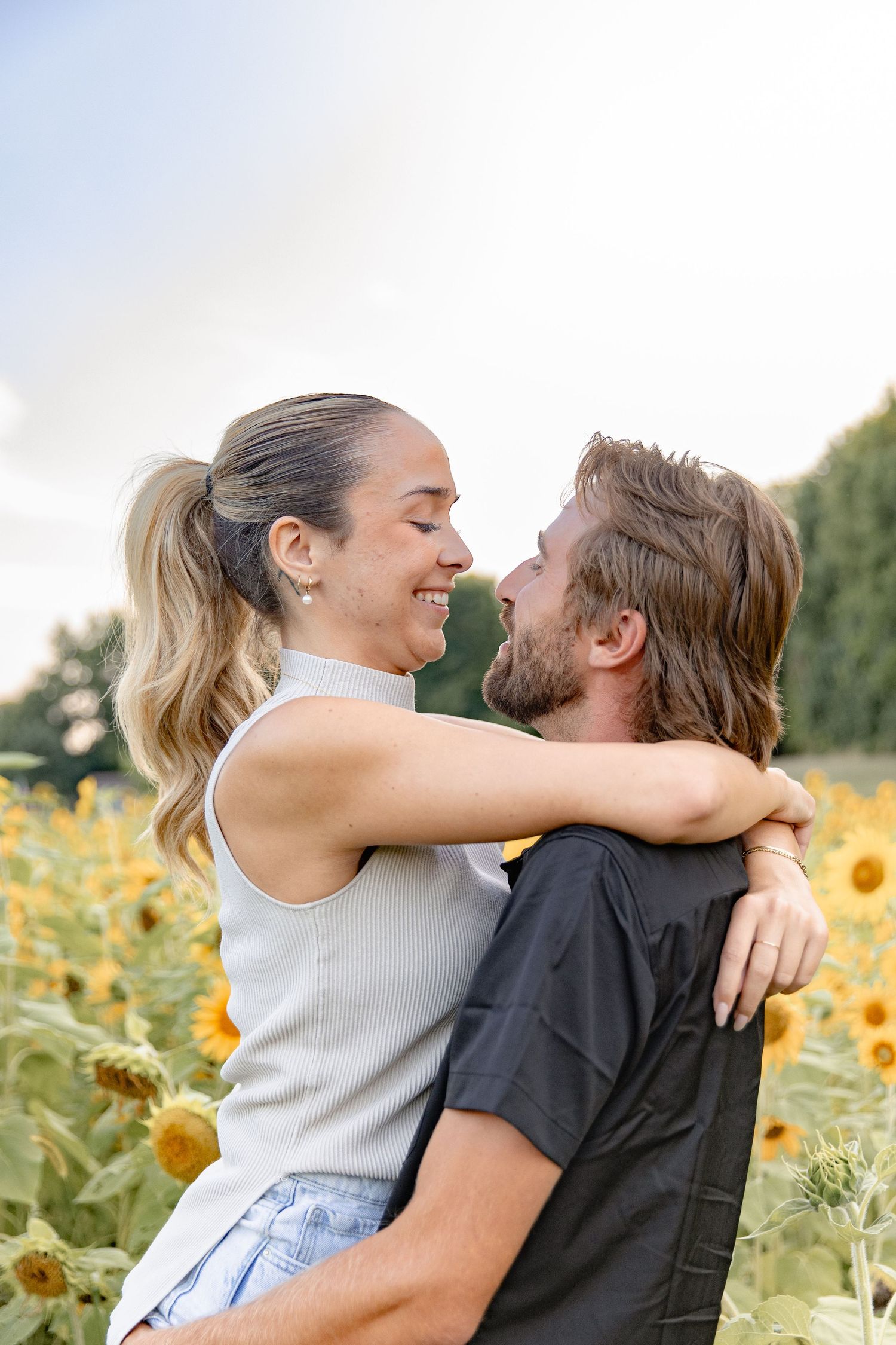 A couple shares romantic moments together in a beautiful sunflower field on a sunny summer day.