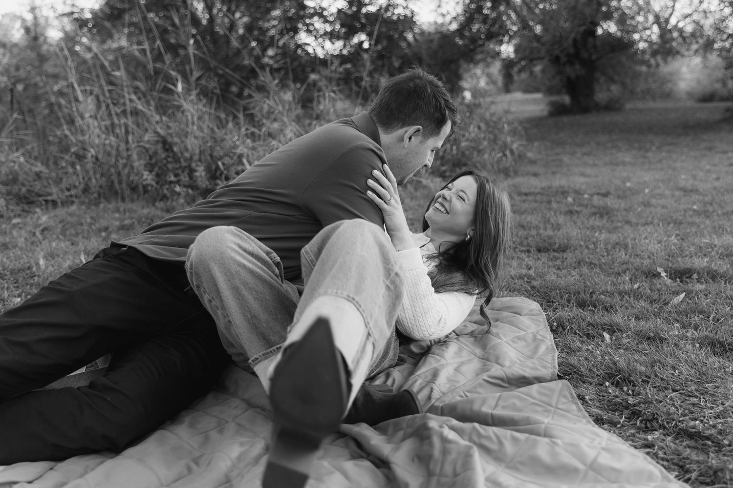 A tender embrace shared in a peaceful natural setting surrounded by trees and grass.