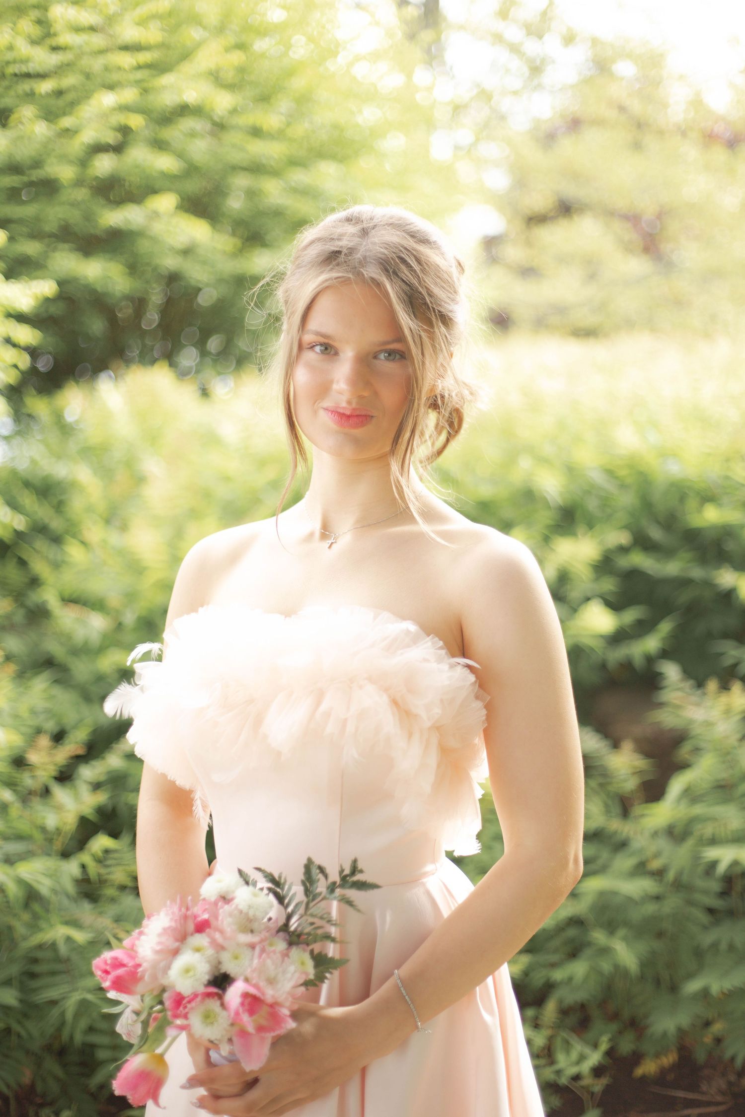 Romantic bridal portraits in soft natural lighting with pink roses and delicate peach gown against lush garden backdrop.