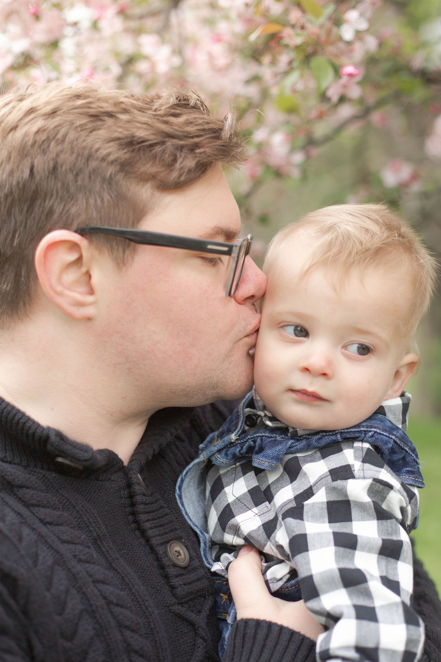 A tender moment shared between parent and child under blooming cherry blossoms in spring.