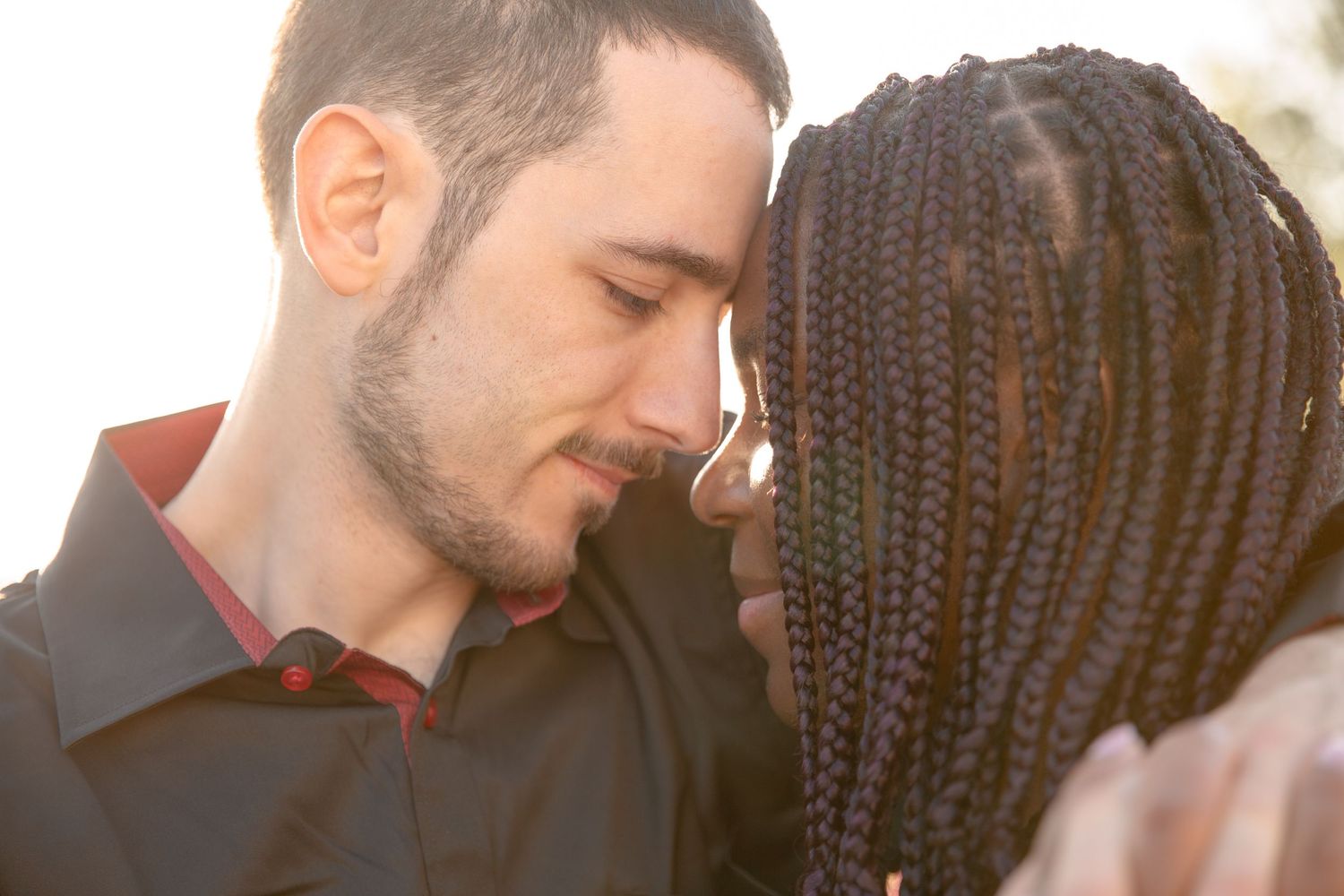 A tender romantic moment between two people sharing an intimate embrace in natural sunlight.