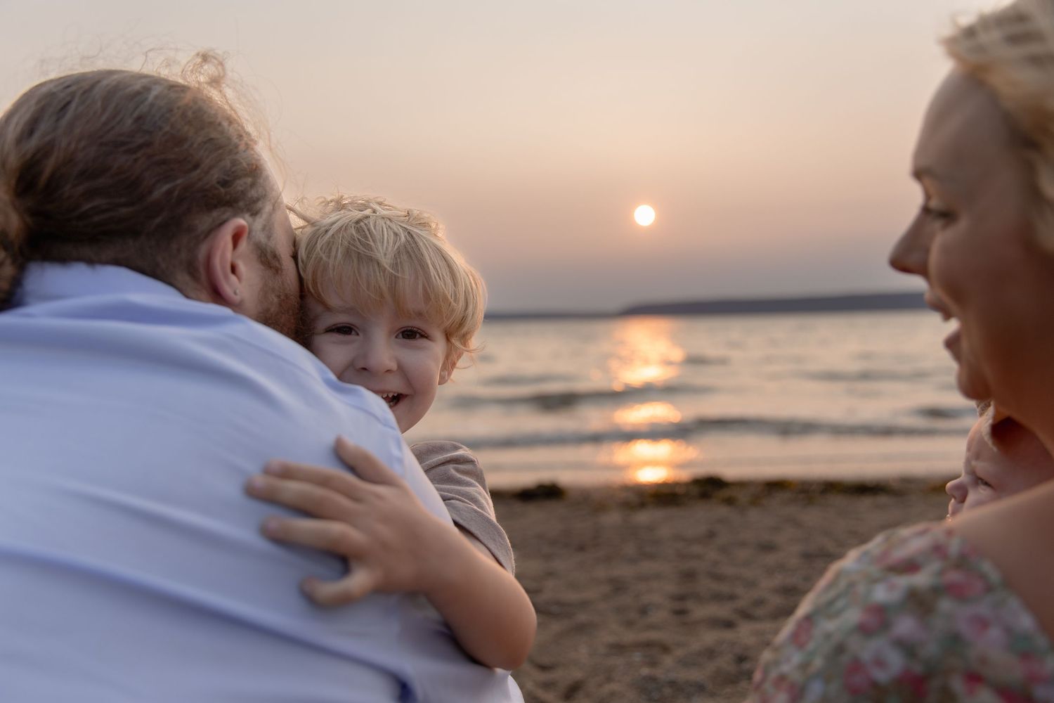 Family enjoying a peaceful sunset walk together along a beautiful sandy beach at dusk.