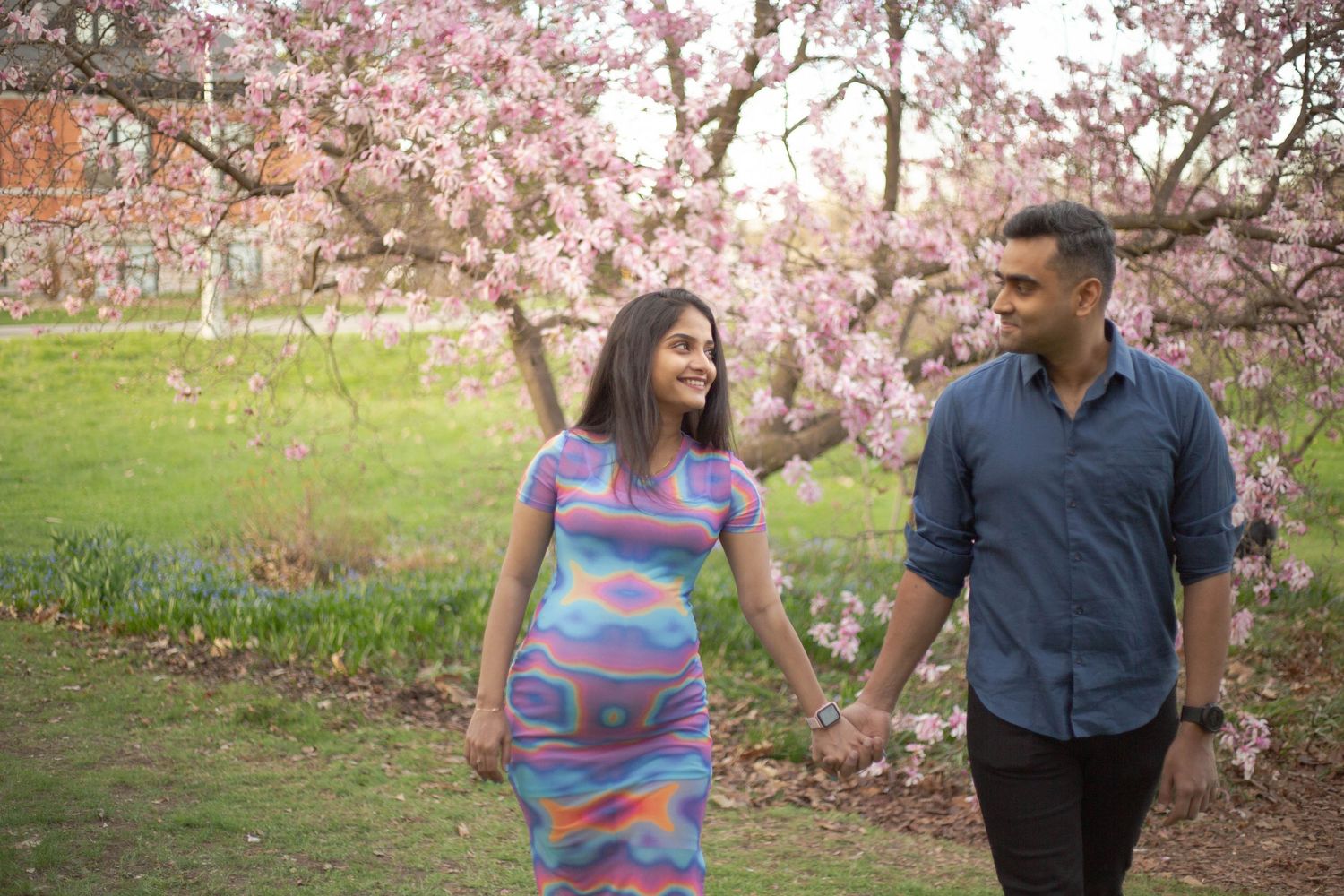 A couple walks together through a blooming cherry blossom garden in springtime.