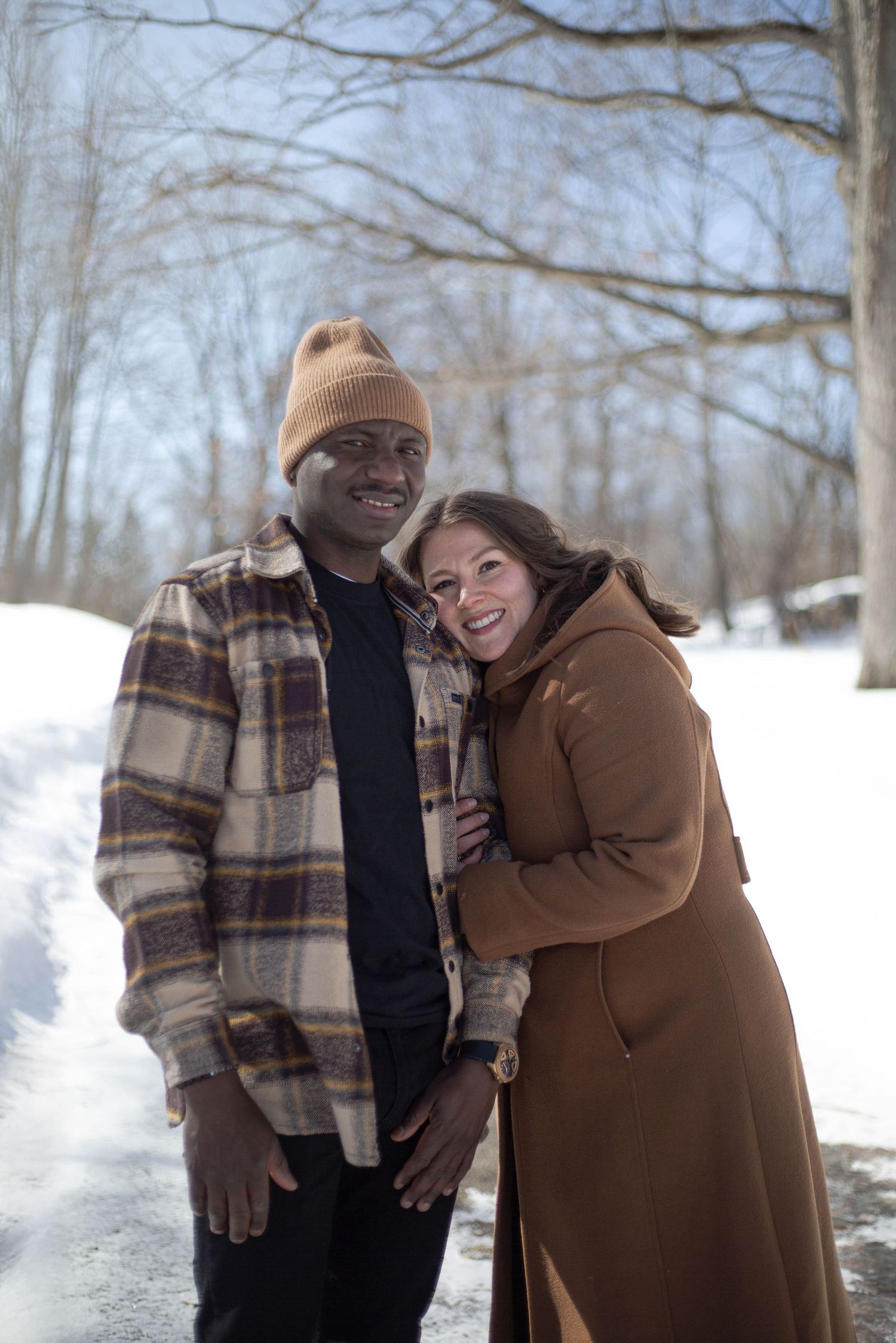 A couple shares a joyful moment together on a snowy winter trail.