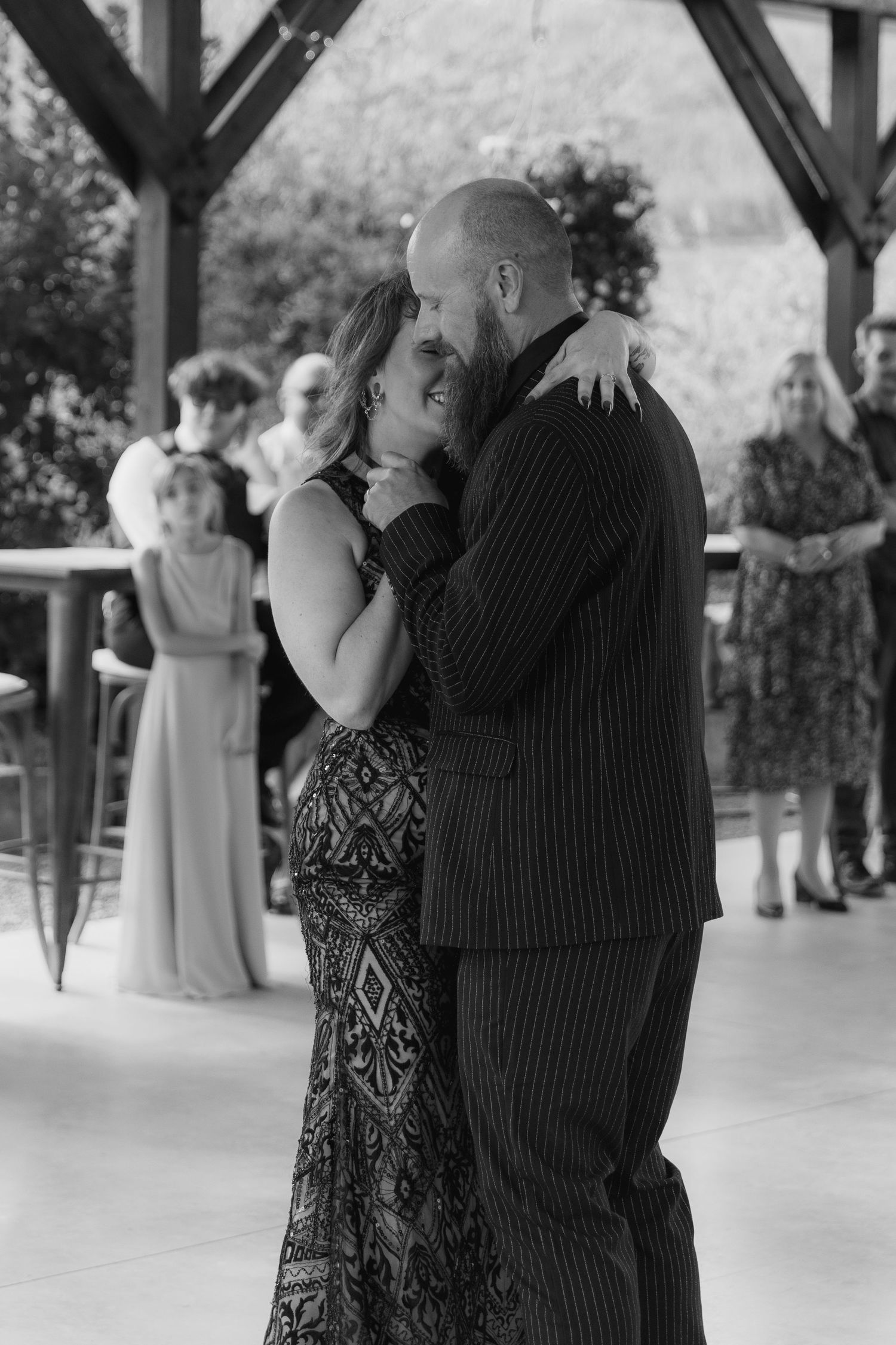 A couple dances together at an outdoor venue, with other people visible in the background.