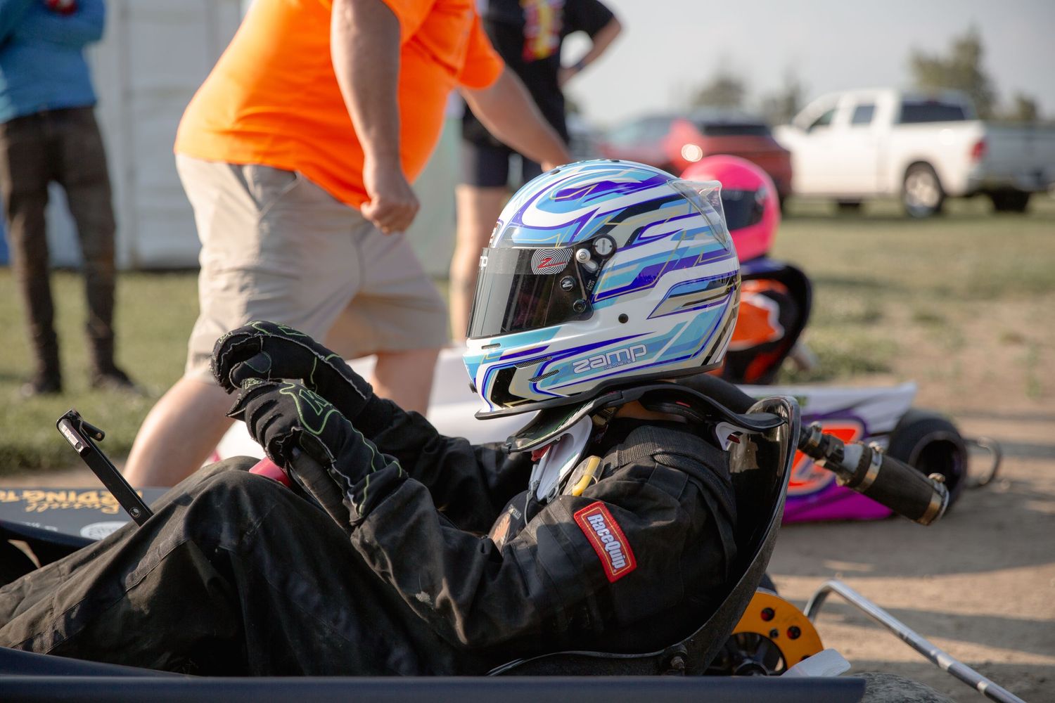 A remote-controlled race car jumps over dirt ramps during an outdoor RC racing event.