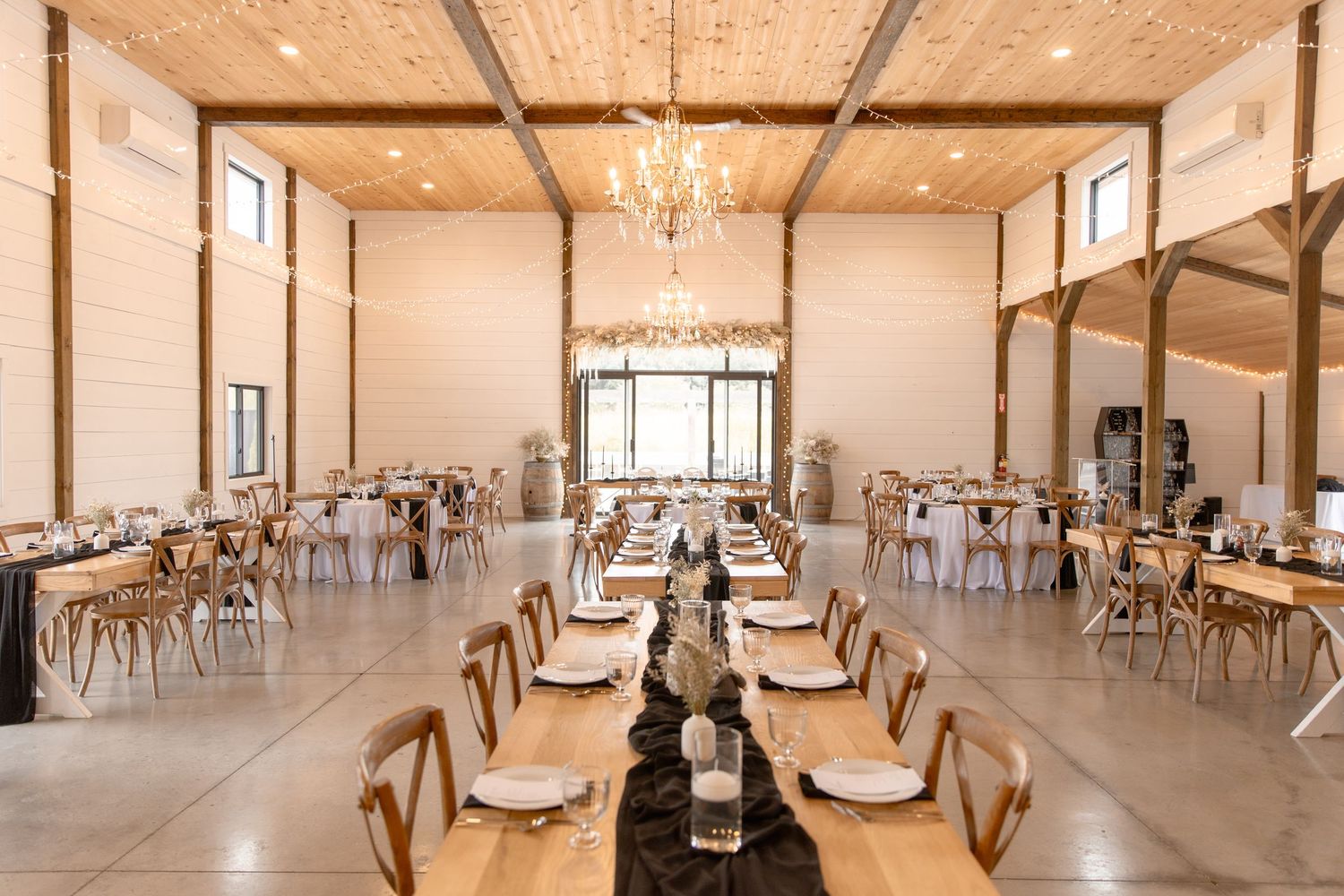 Large elegant banquet hall with crystal chandeliers and wooden tables set for a formal event.