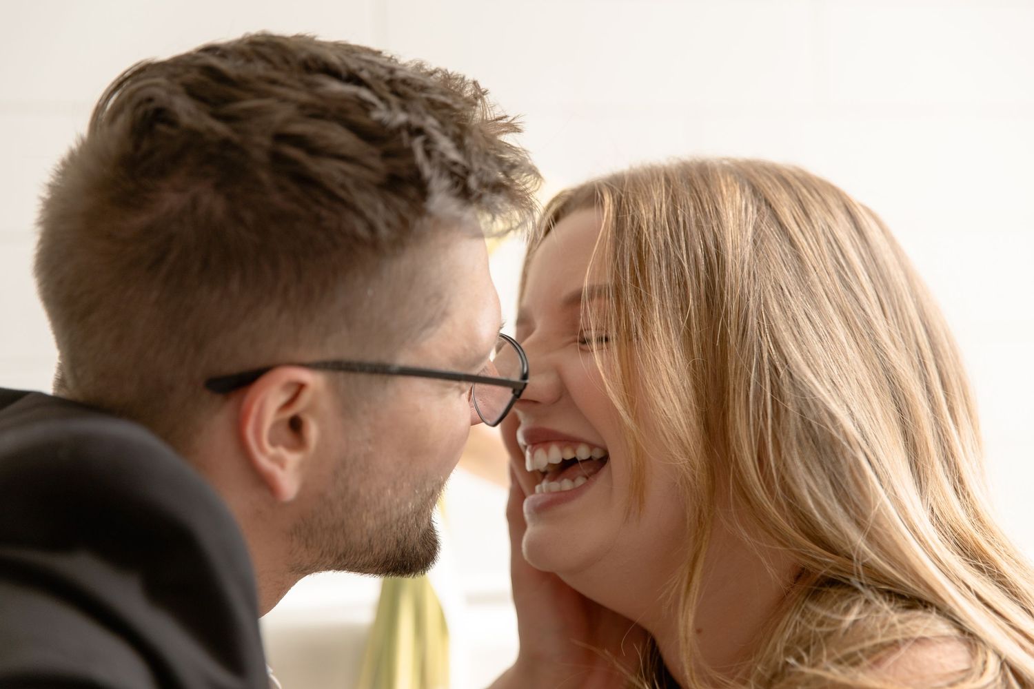 An intimate close-up shot showing affectionate interaction between two people in soft lighting.