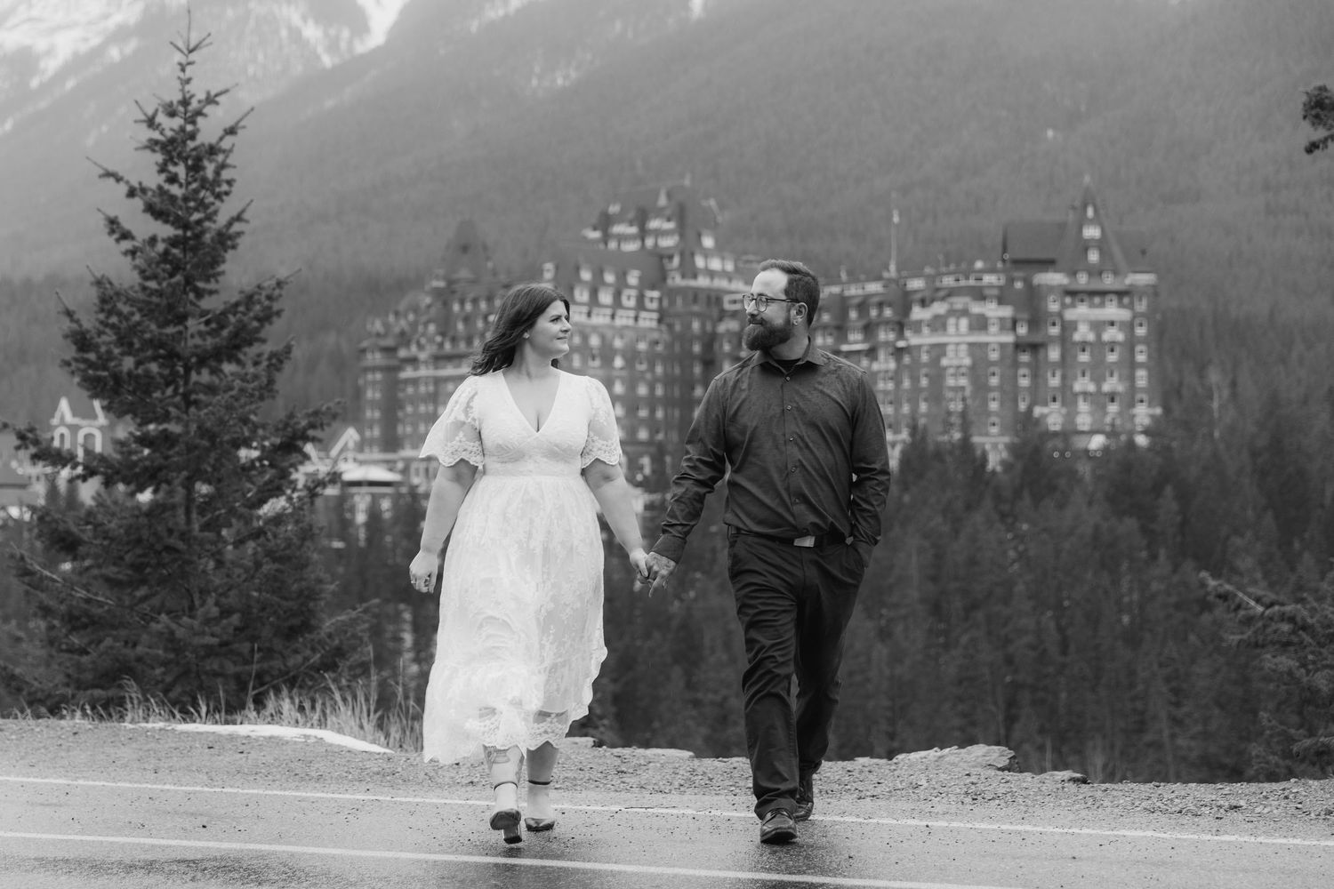 A black and white panoramic view of a mountain resort hotel nestled among evergreen trees in a snowy landscape.