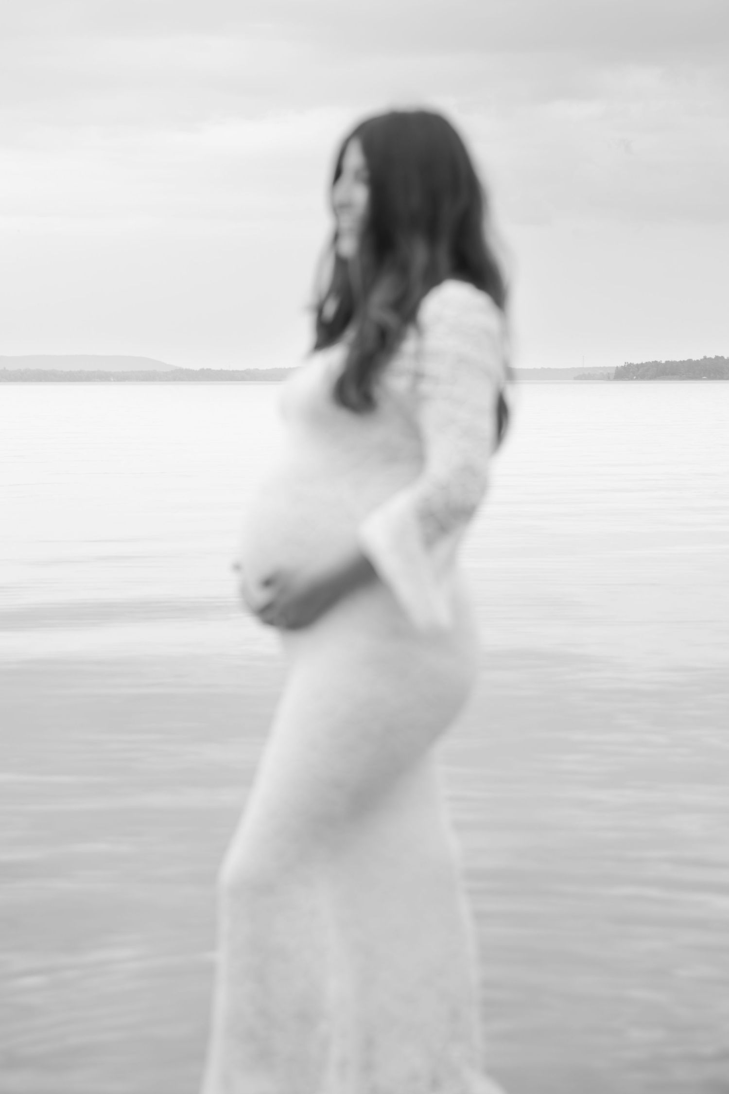 Ethereal silhouette of a figure in white dress dancing on a misty beach shoreline.