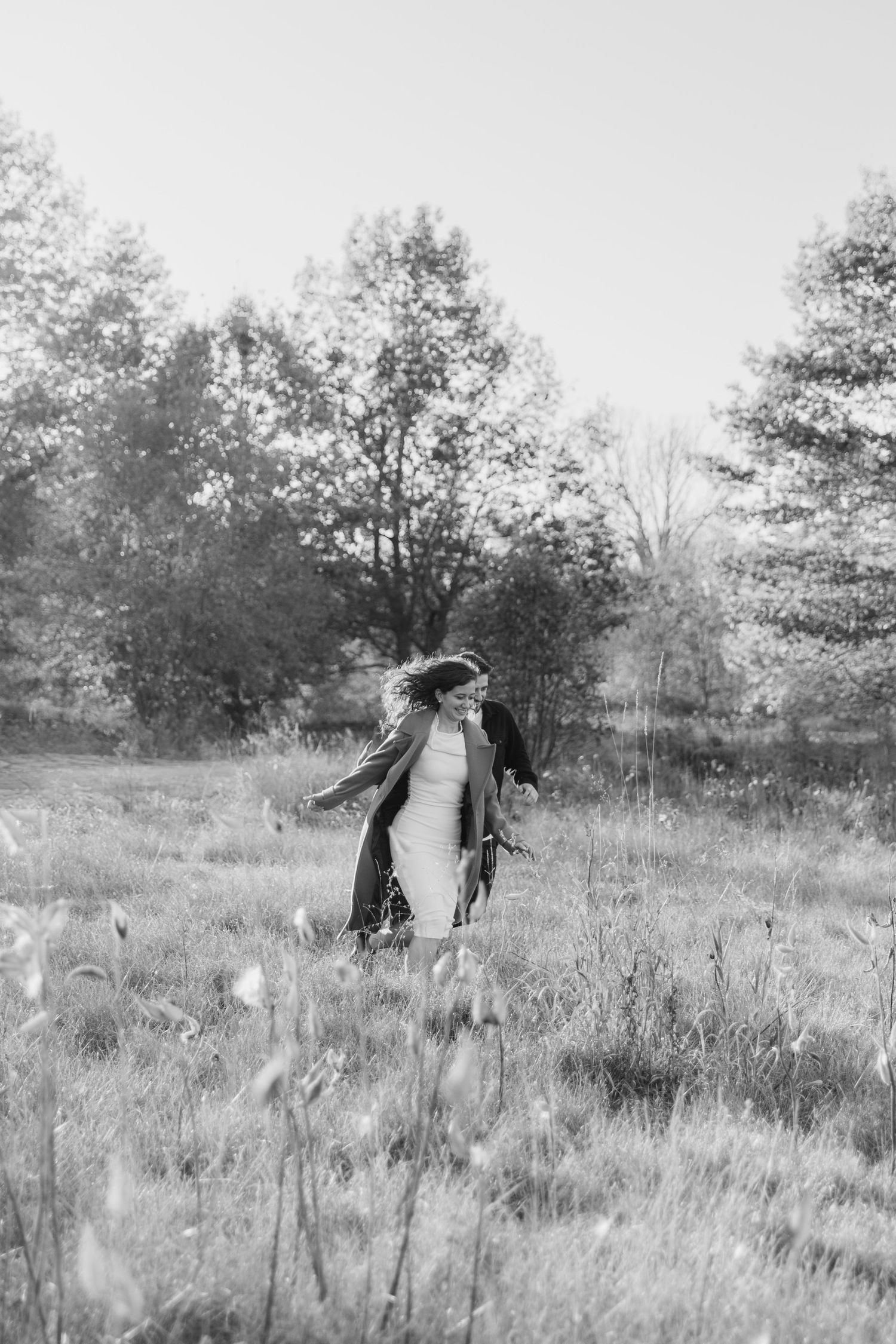 A scarecrow stands in a grassy meadow with trees in the background on a misty autumn day.