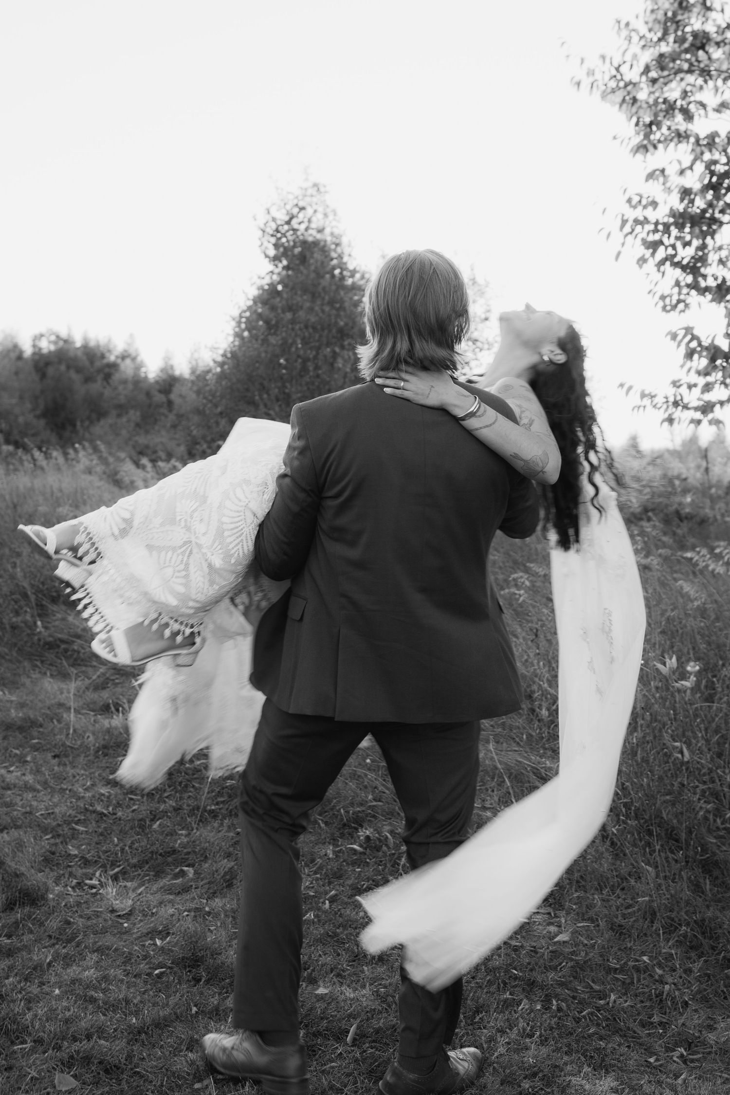 A sequence of black and white photos shows a person playfully twirling with a flowing white fabric in nature.
