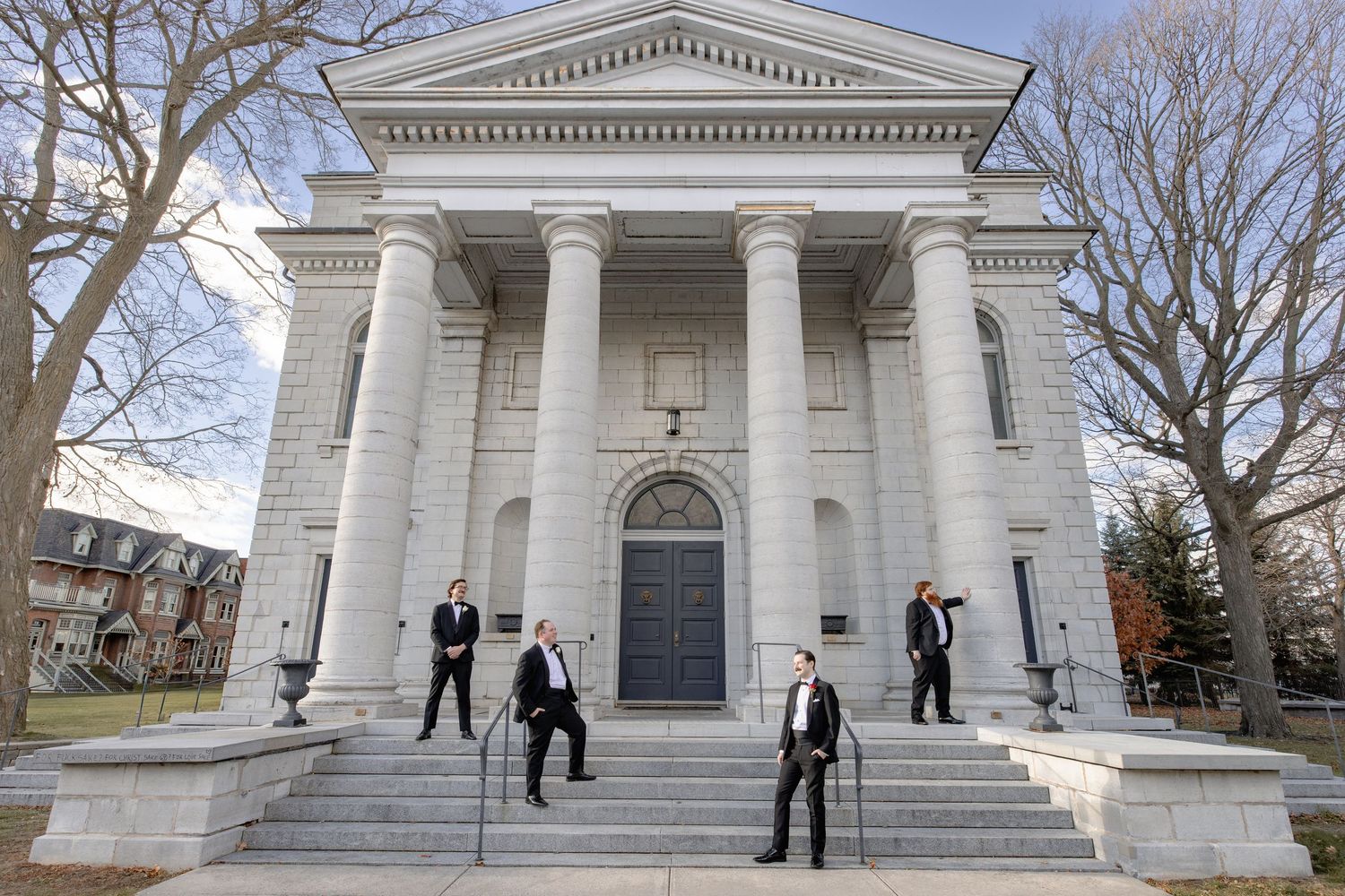 Classical white stone building with columns and steps in winter, with people walking on the stairs.