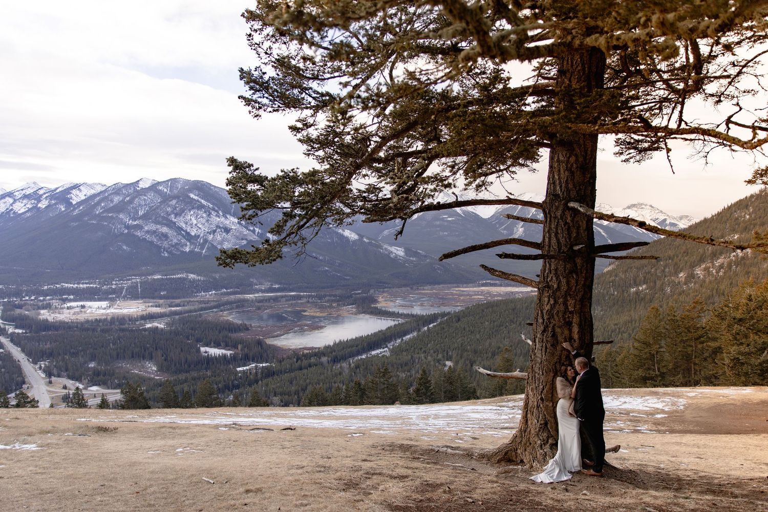 A panoramic mountain landscape with snow-capped peaks and evergreen trees framing the scenic winter vista.