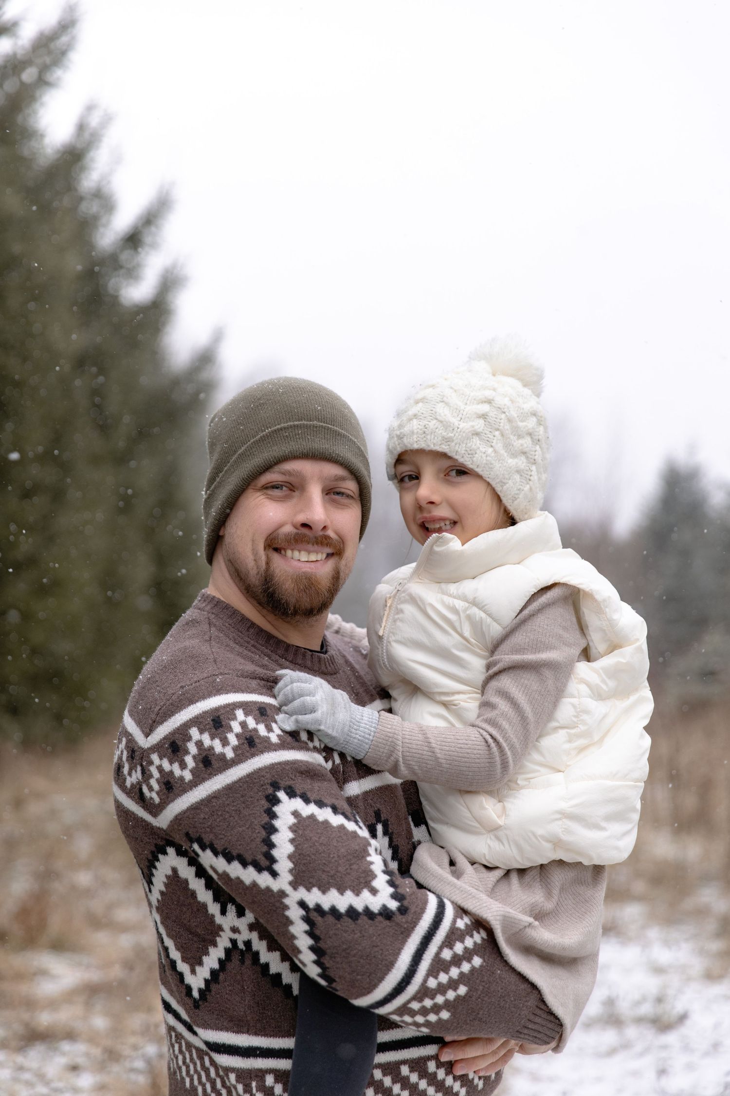 A joyful winter scene with two people wearing cozy sweaters and knit hats playing in the snow.
