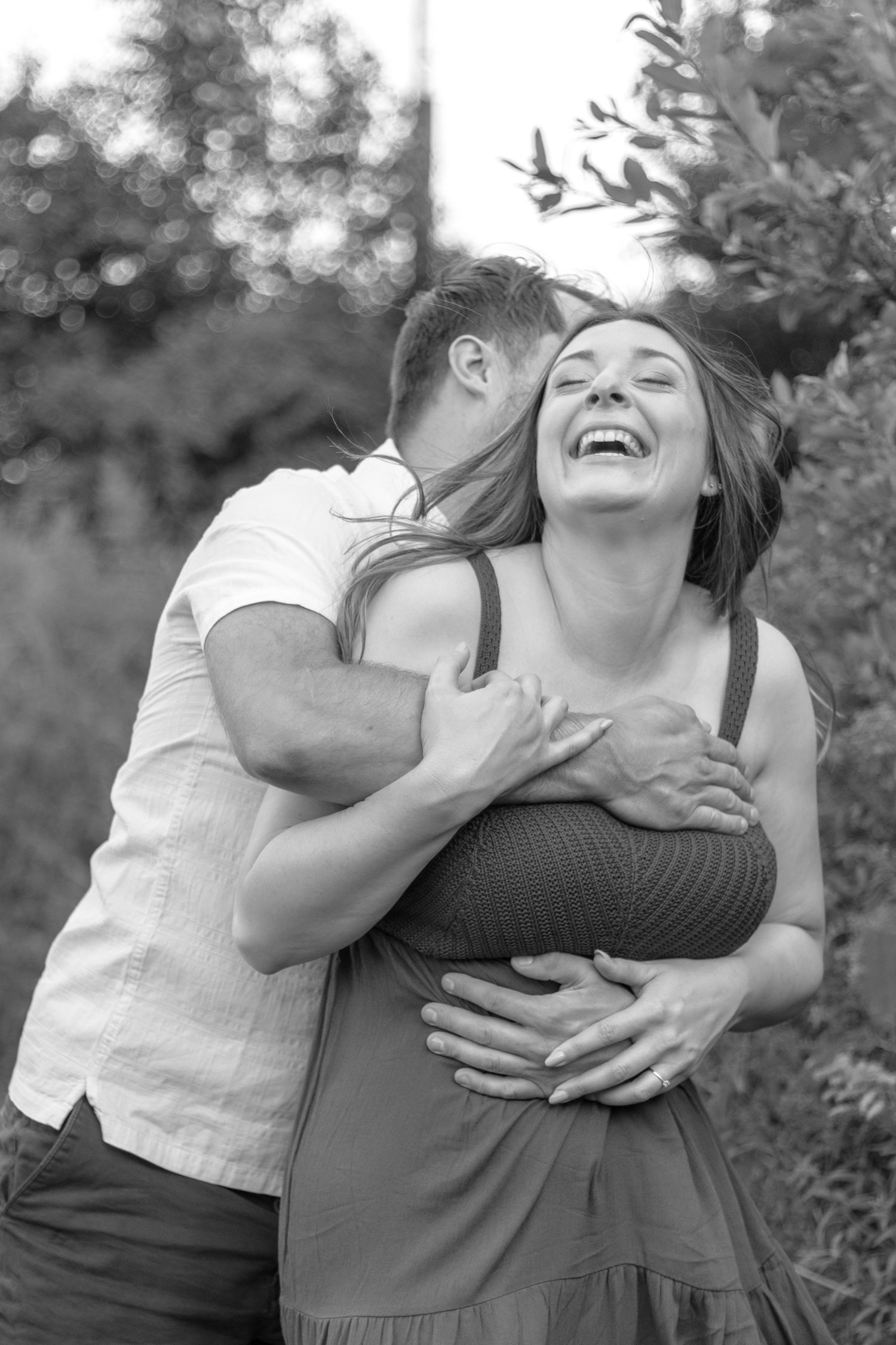 A couple shares joyful laughter and embraces in a candid black and white photo series.
