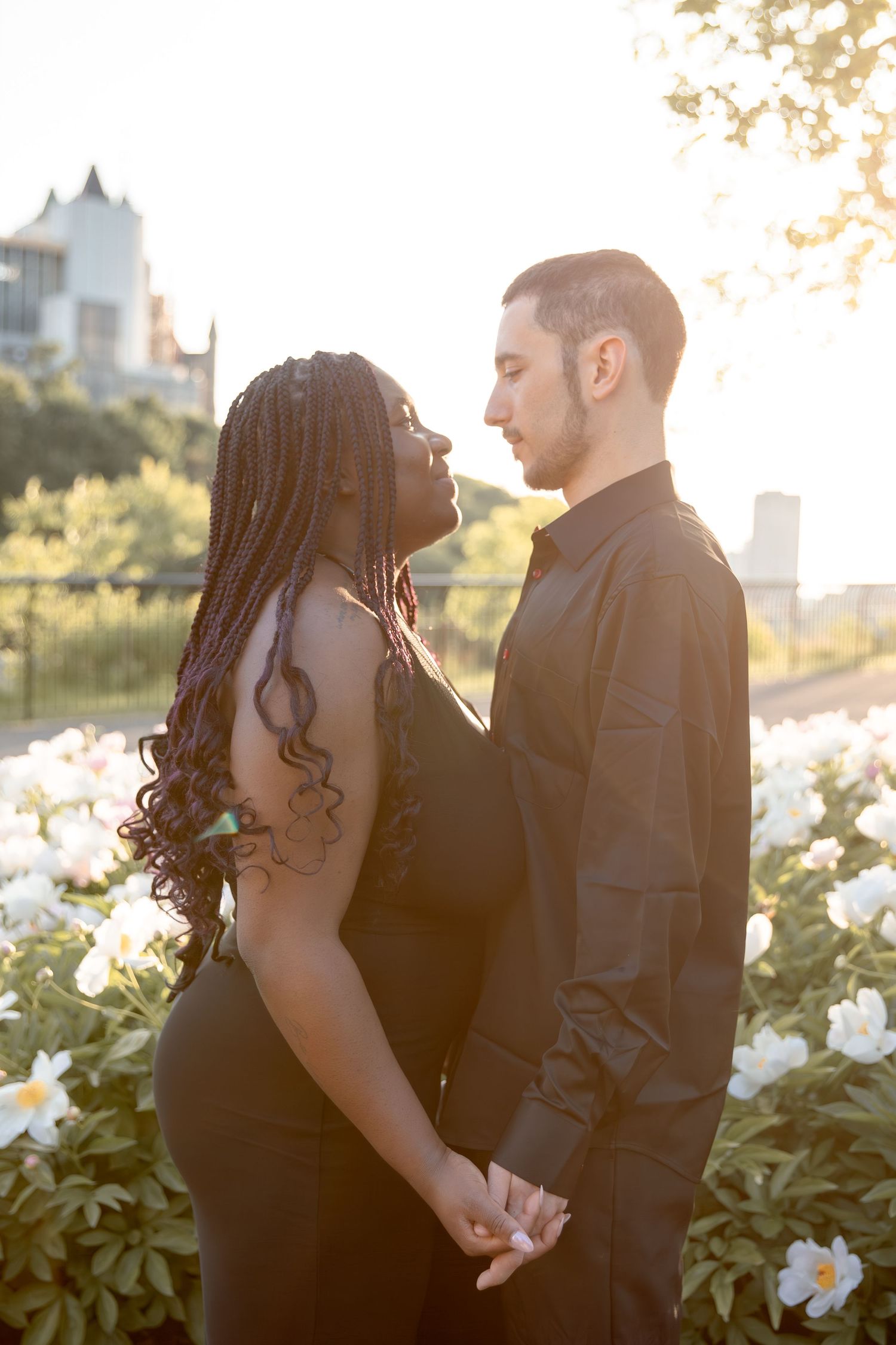 Romantic couple poses together during golden hour engagement photoshoot in a garden setting.