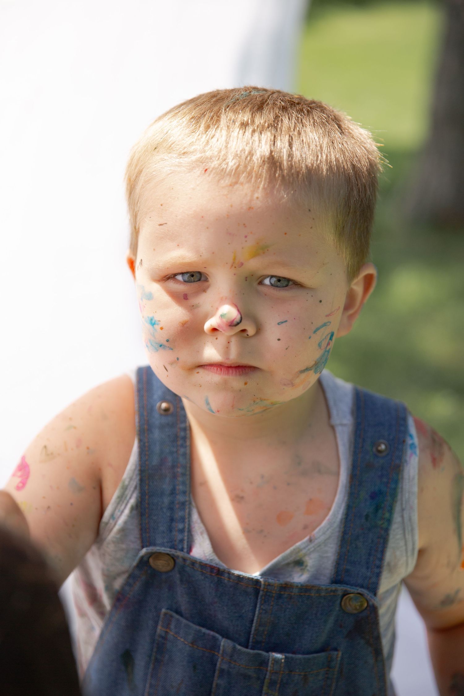 A series of four close-up shots showing a child in denim overalls with dirt smudges on their face.