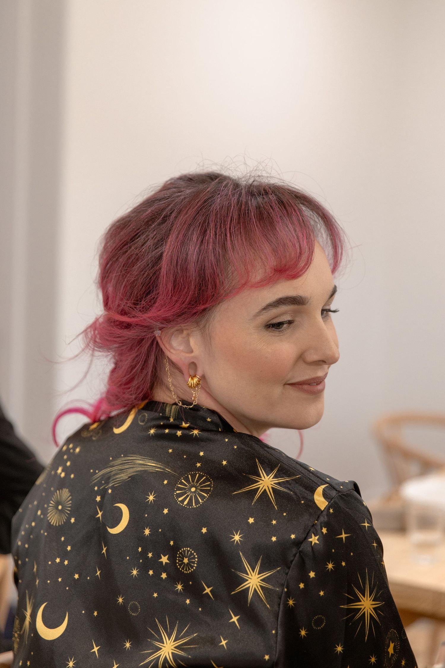 Person wearing a black jacket decorated with gold celestial motifs including stars, moons and sparkles.