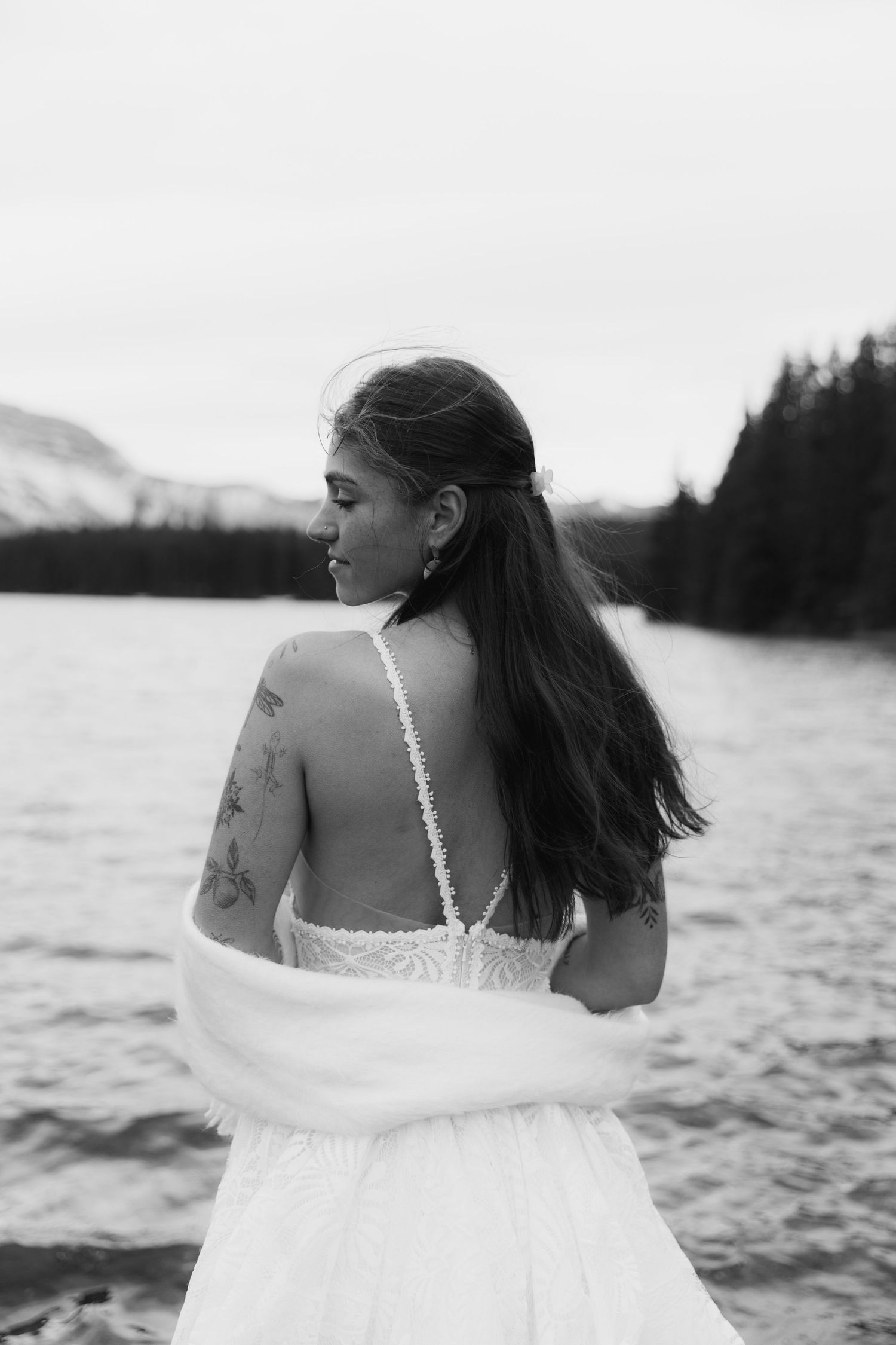 Black and white artistic wedding photos show bride in flowing white dress against scenic lake backdrop.