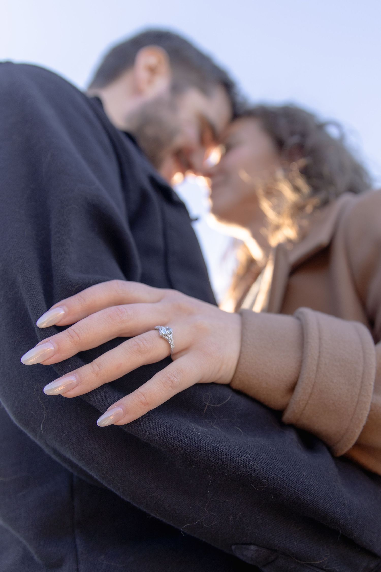 Close-up photo sequence showing an engagement ring on a hand resting against a dark fabric background.