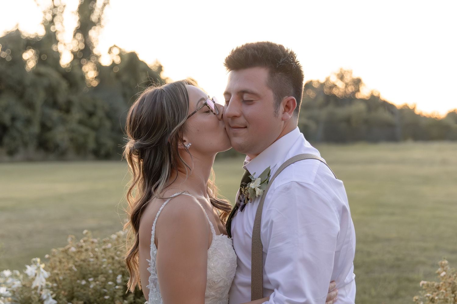 Romantic sunset wedding portraits of a couple embracing in a golden field.