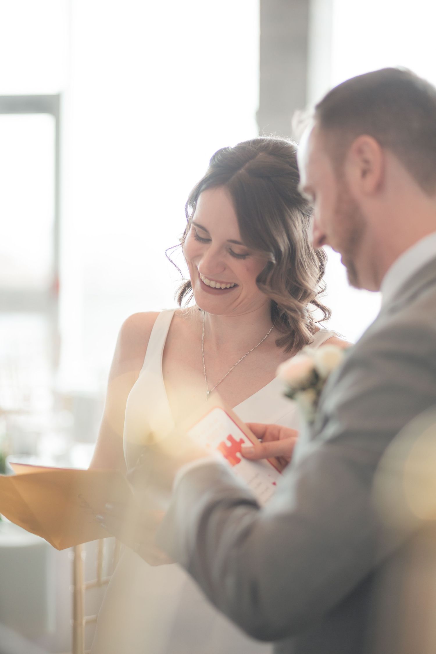 Smiling bride and groom signing wedding documents during their ceremony in bright natural light.