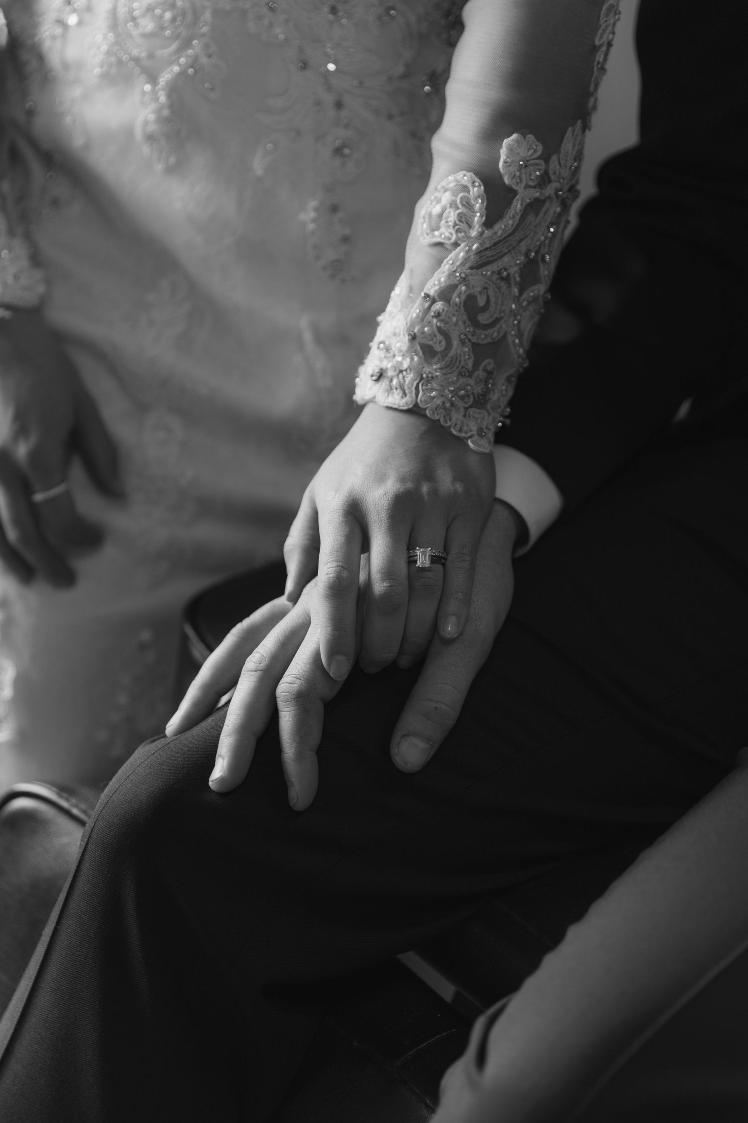 Close-up of hands wearing lace sleeve detail and engagement ring.