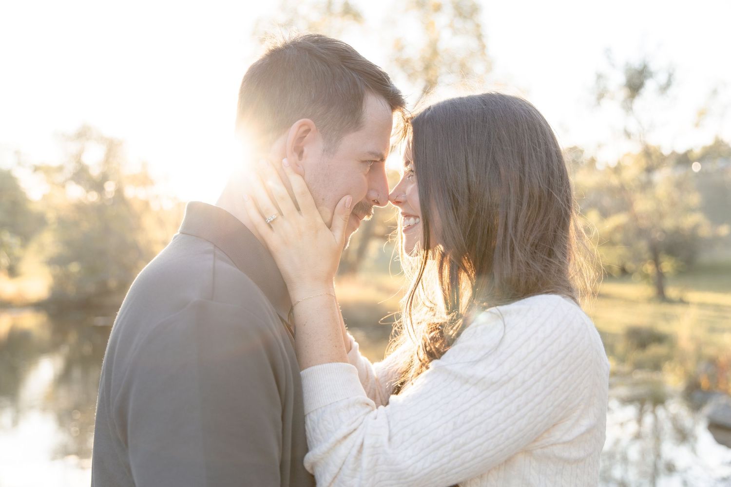 A couple shares a romantic moment during a golden sunset in a park setting.