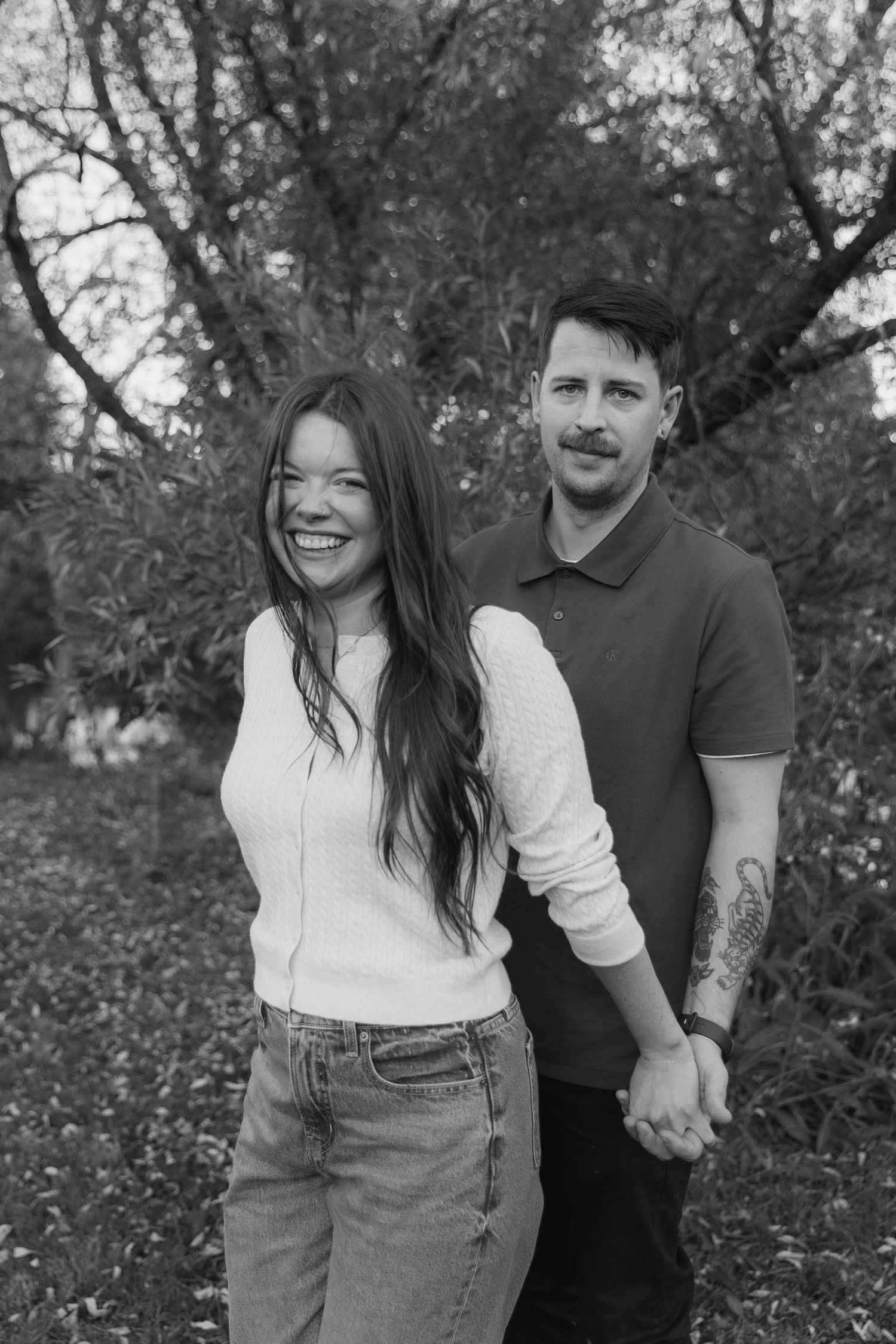 A couple shares a joyful moment together outdoors in black and white photography.