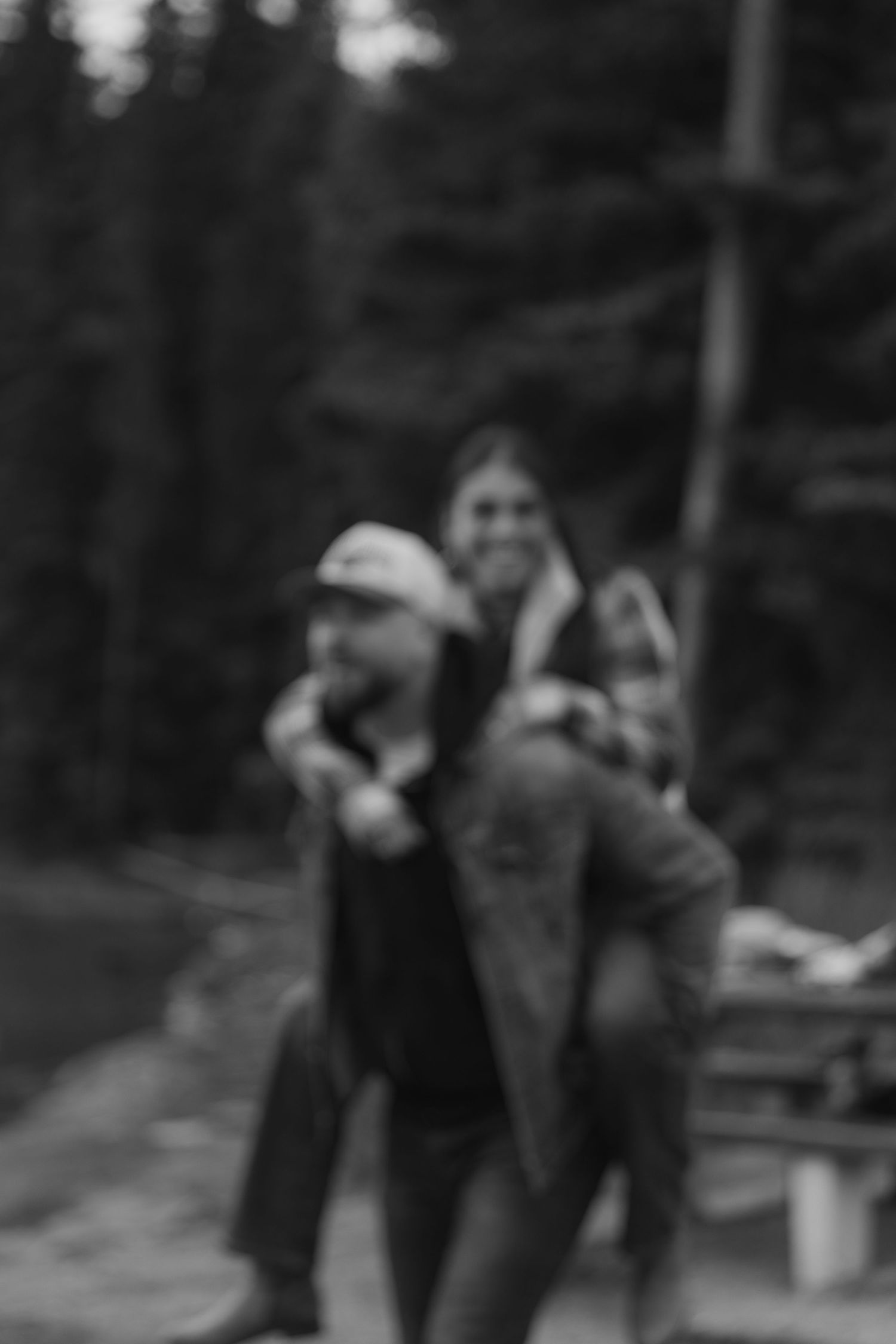 A black and white vintage photograph shows people walking together in a wooded outdoor setting.