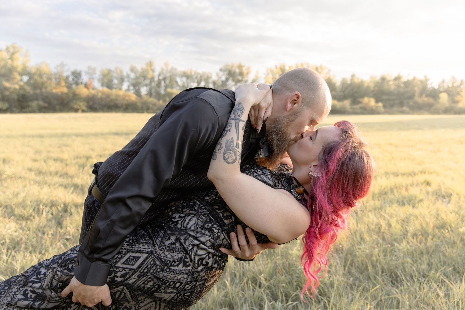 Couple sharing an intimate moment in a sunlit meadow at golden hour.