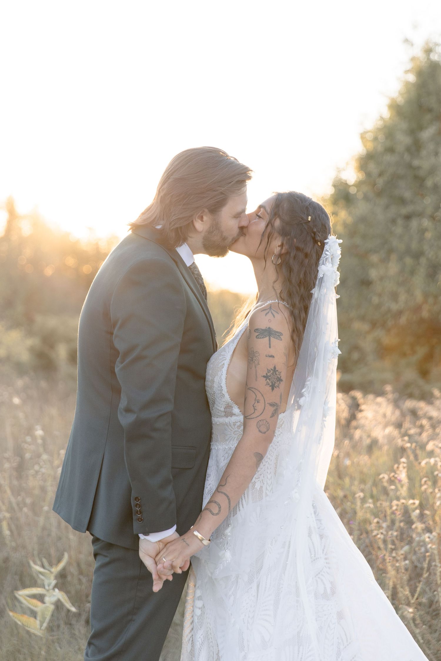 A romantic sunset wedding photoshoot shows a couple sharing tender moments in a golden meadow field.