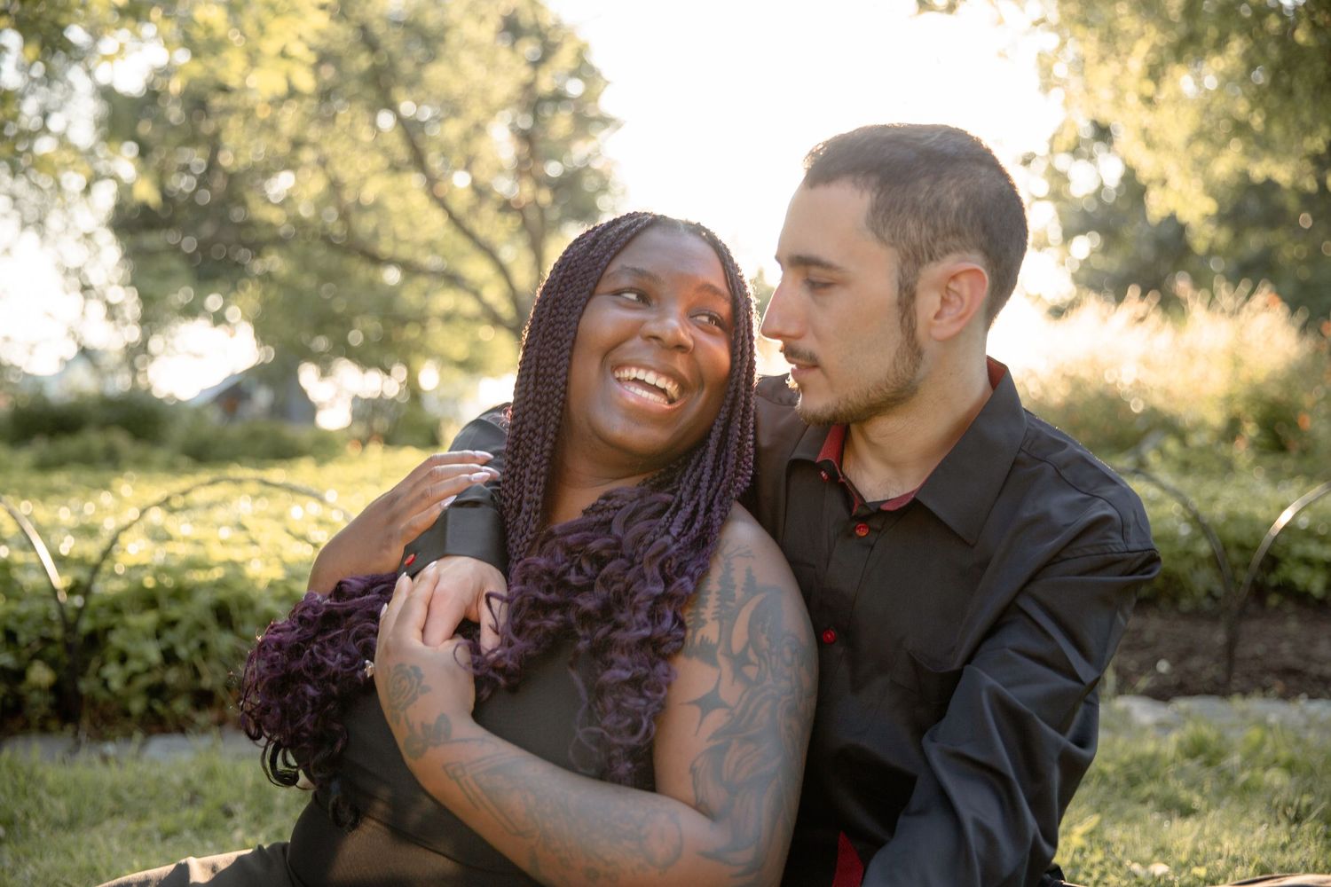 Couple shares intimate moment together during golden hour photoshoot in outdoor garden setting.
