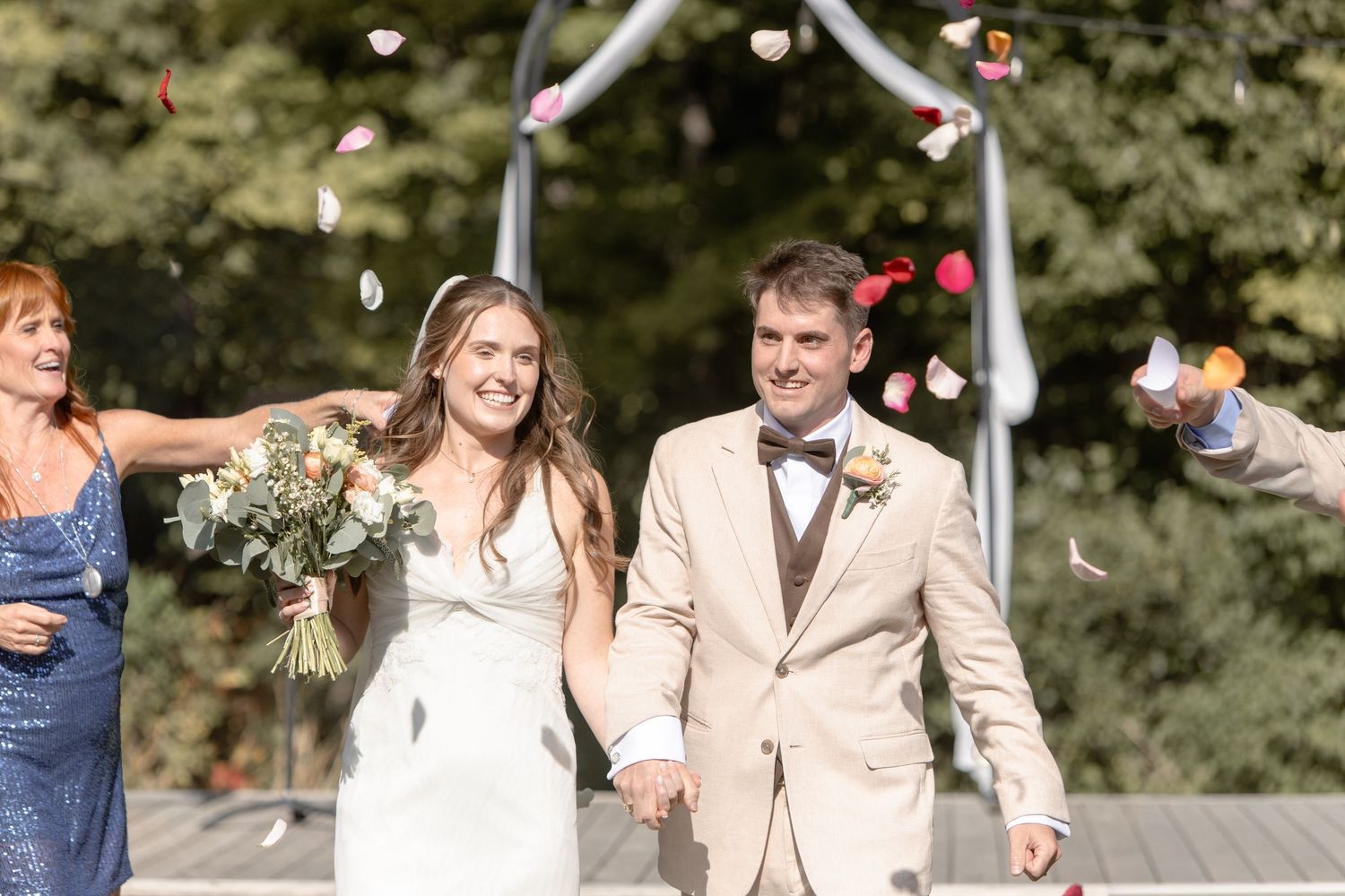 Wedding couple and guests celebrate with confetti toss in outdoor garden setting.