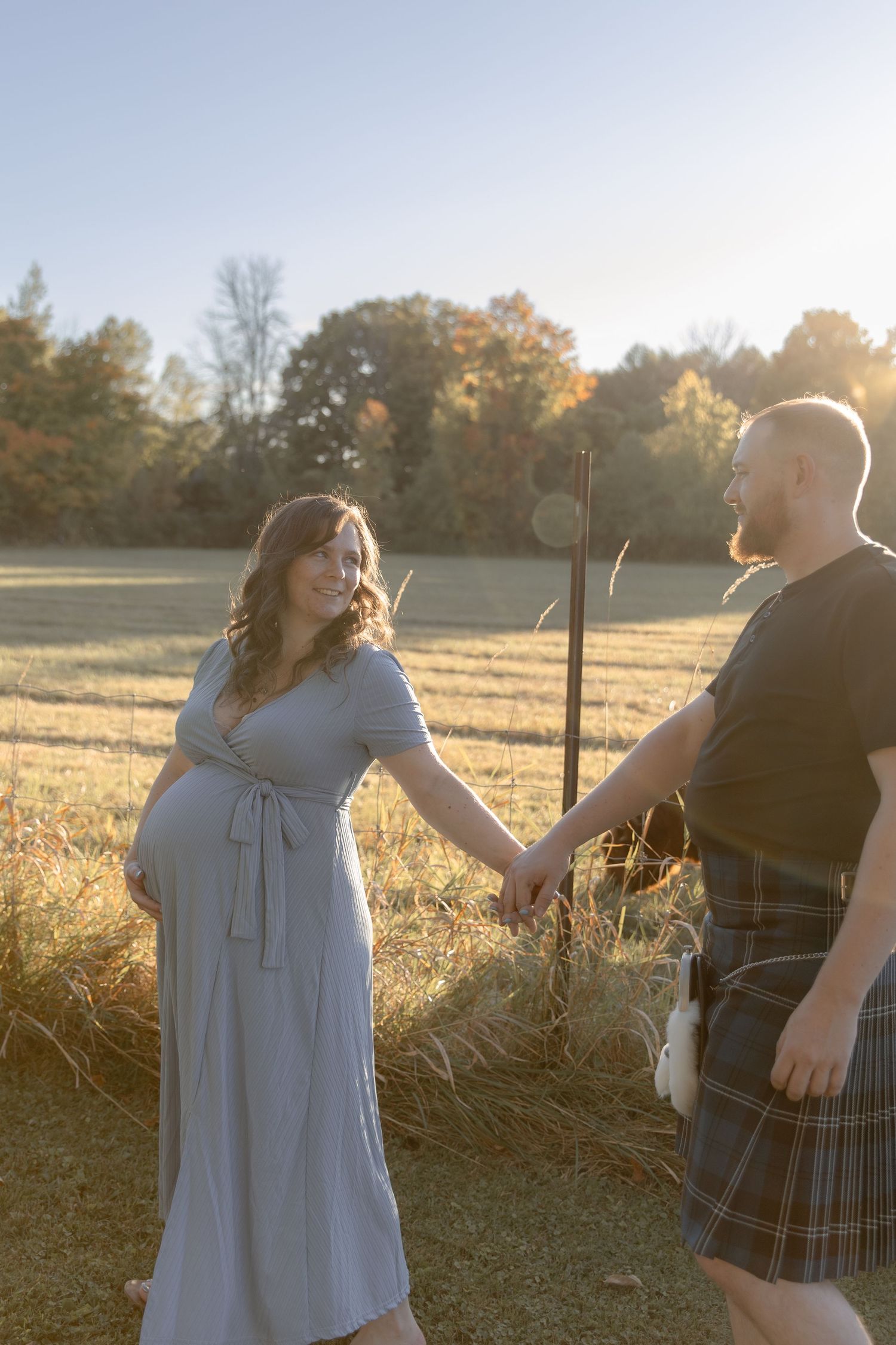 People in contrasting outfits share a joyful moment together in a golden-lit field at dusk.