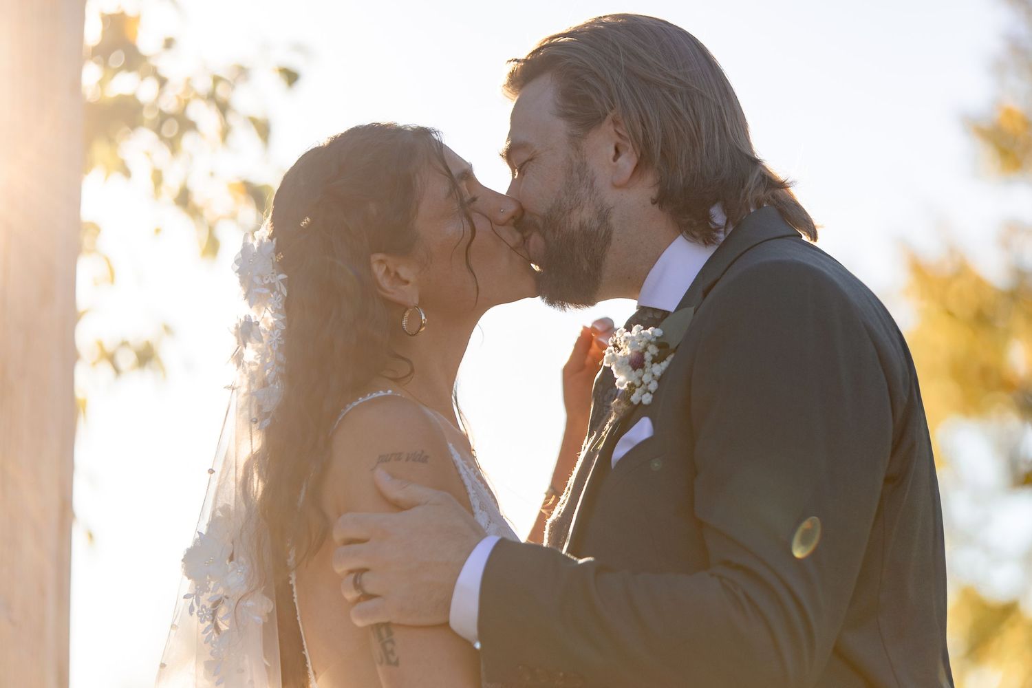 A couple embraces during a romantic sunset photoshoot with golden light filtering through trees.