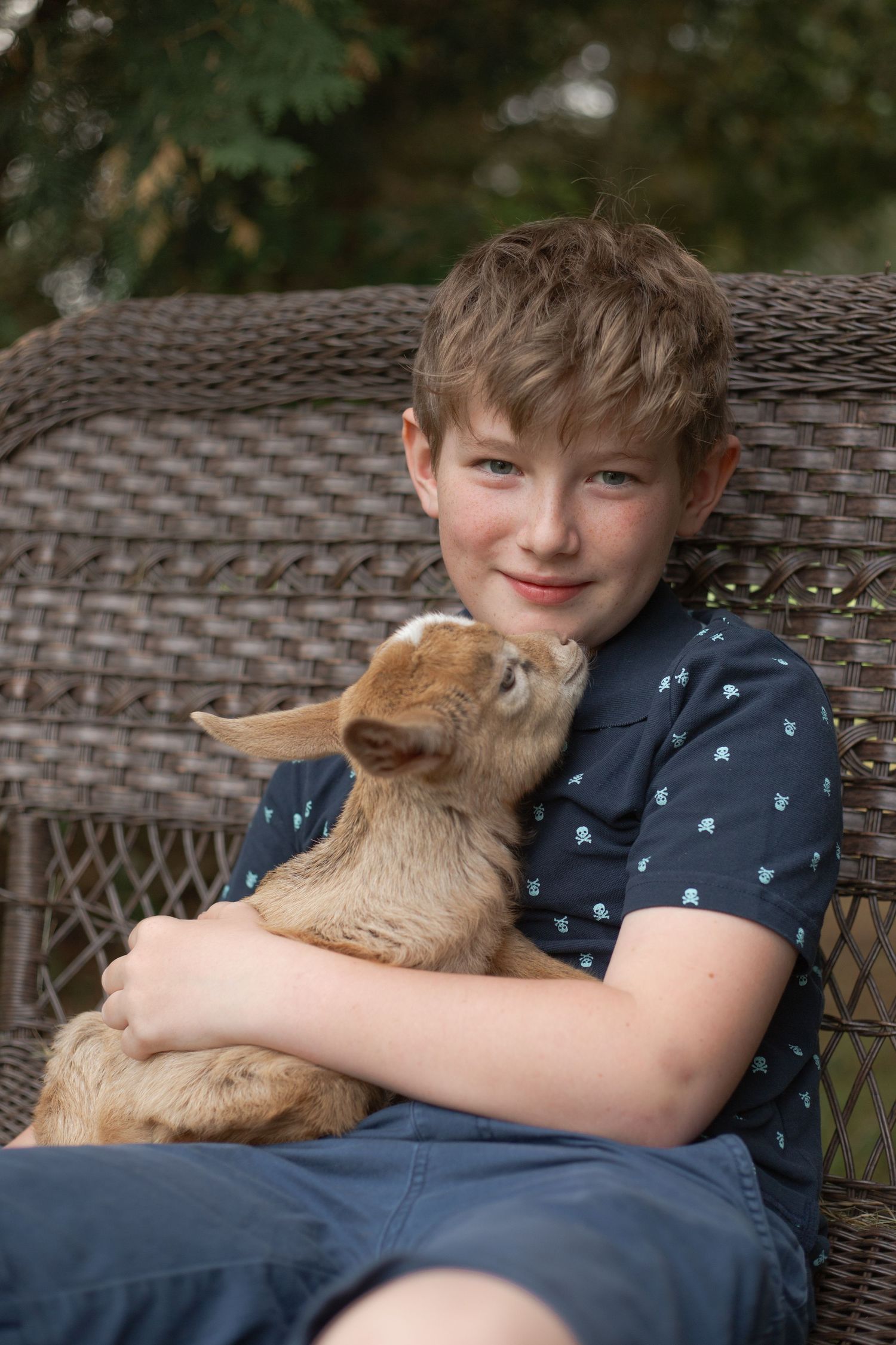 A brown rabbit snuggles with someone sitting on wicker patio furniture outdoors.