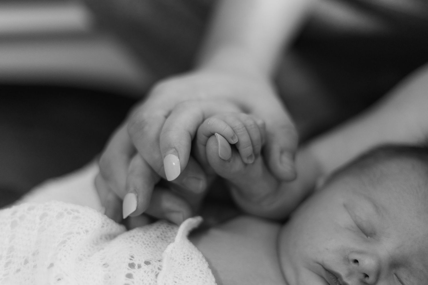 Black and white close-up photo of hands creating a small origami paper craft on a flat surface.