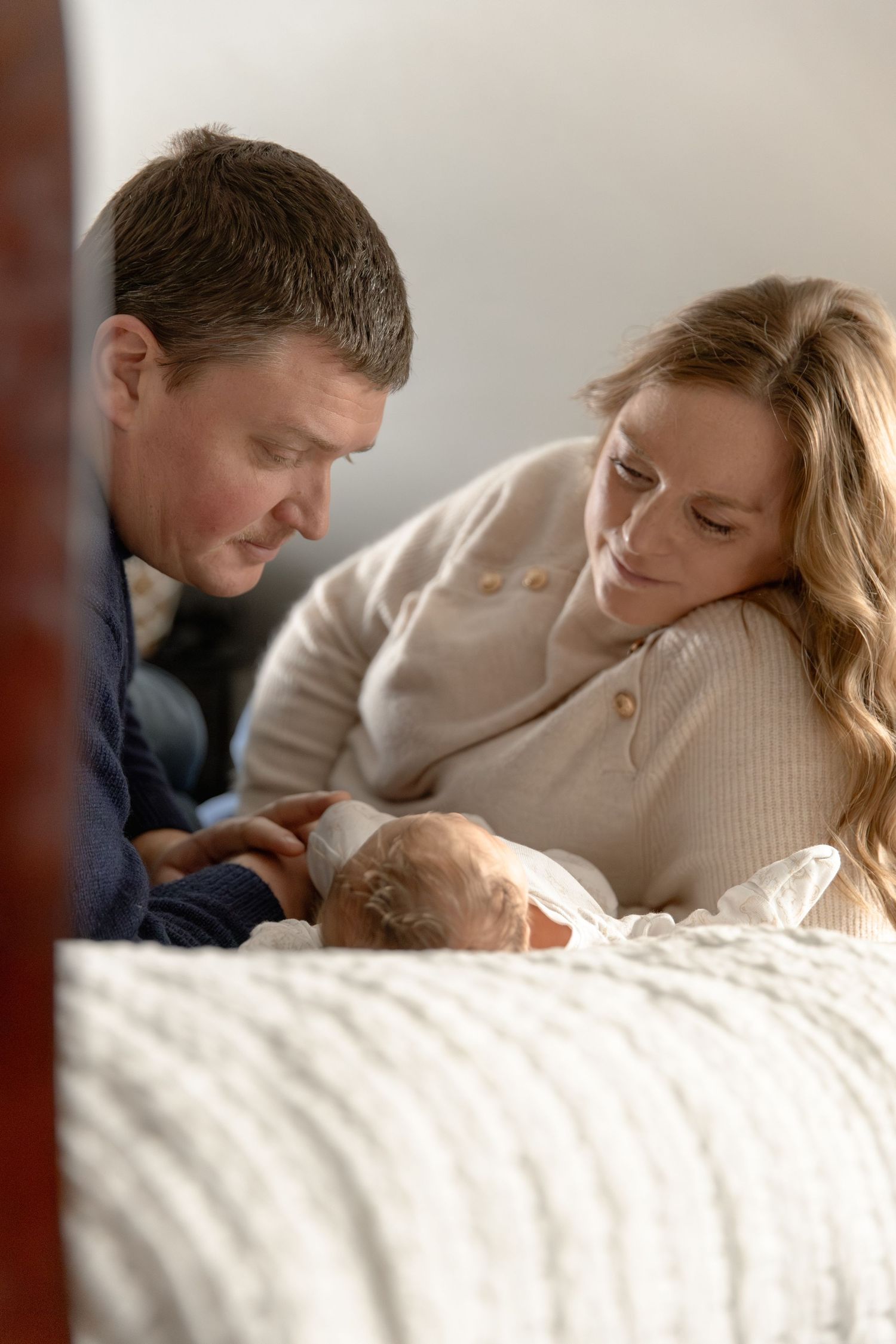 Sequence of tender moments between parent and sleeping baby in white bedding.