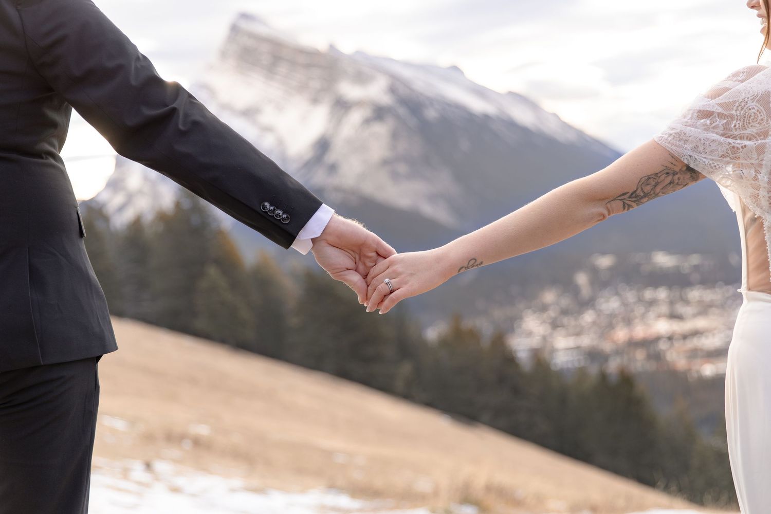 Couple holding hands while dancing against snowy mountain landscape.