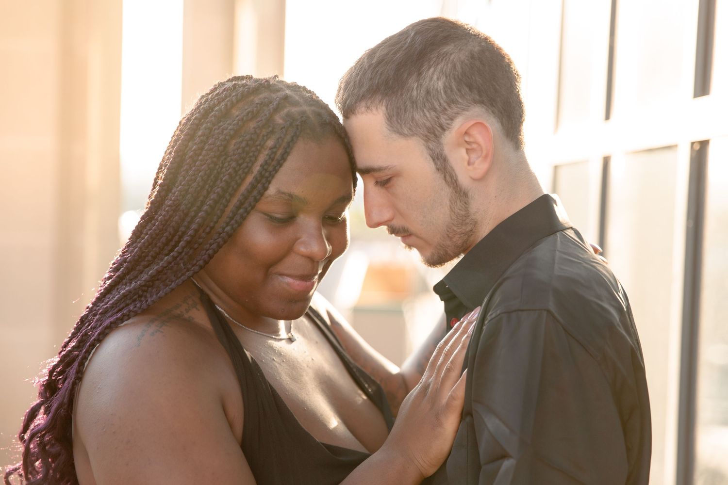 A couple embraces tenderly during a romantic outdoor photoshoot with warm lighting.