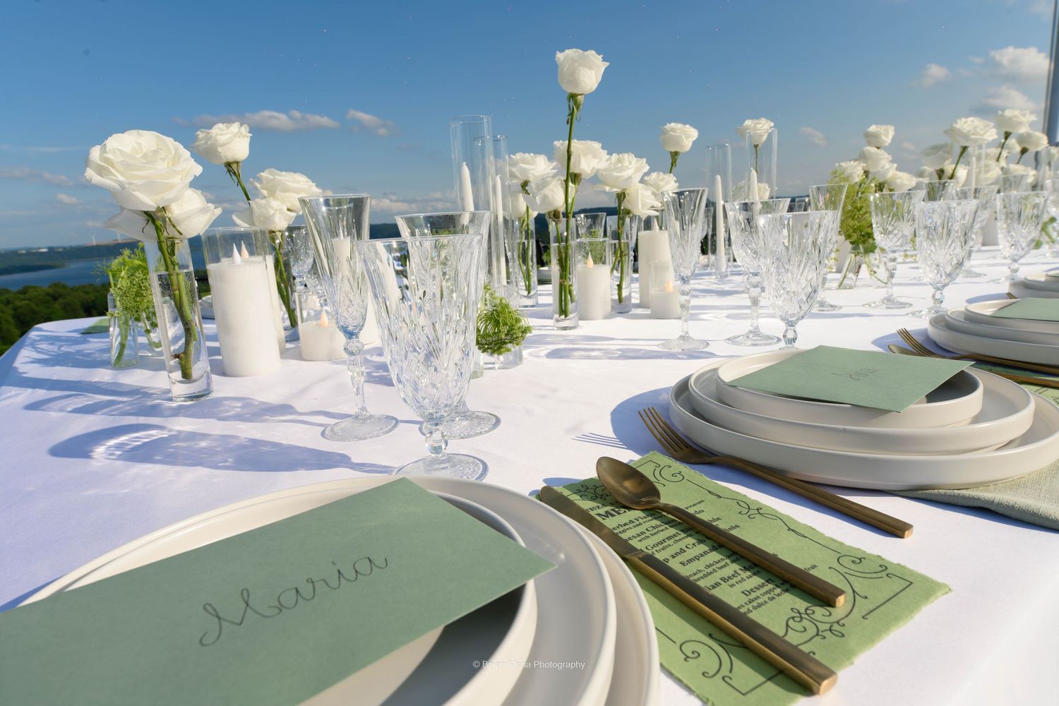 Elegant white table settings with floral centerpieces and glassware arranged for a formal event.