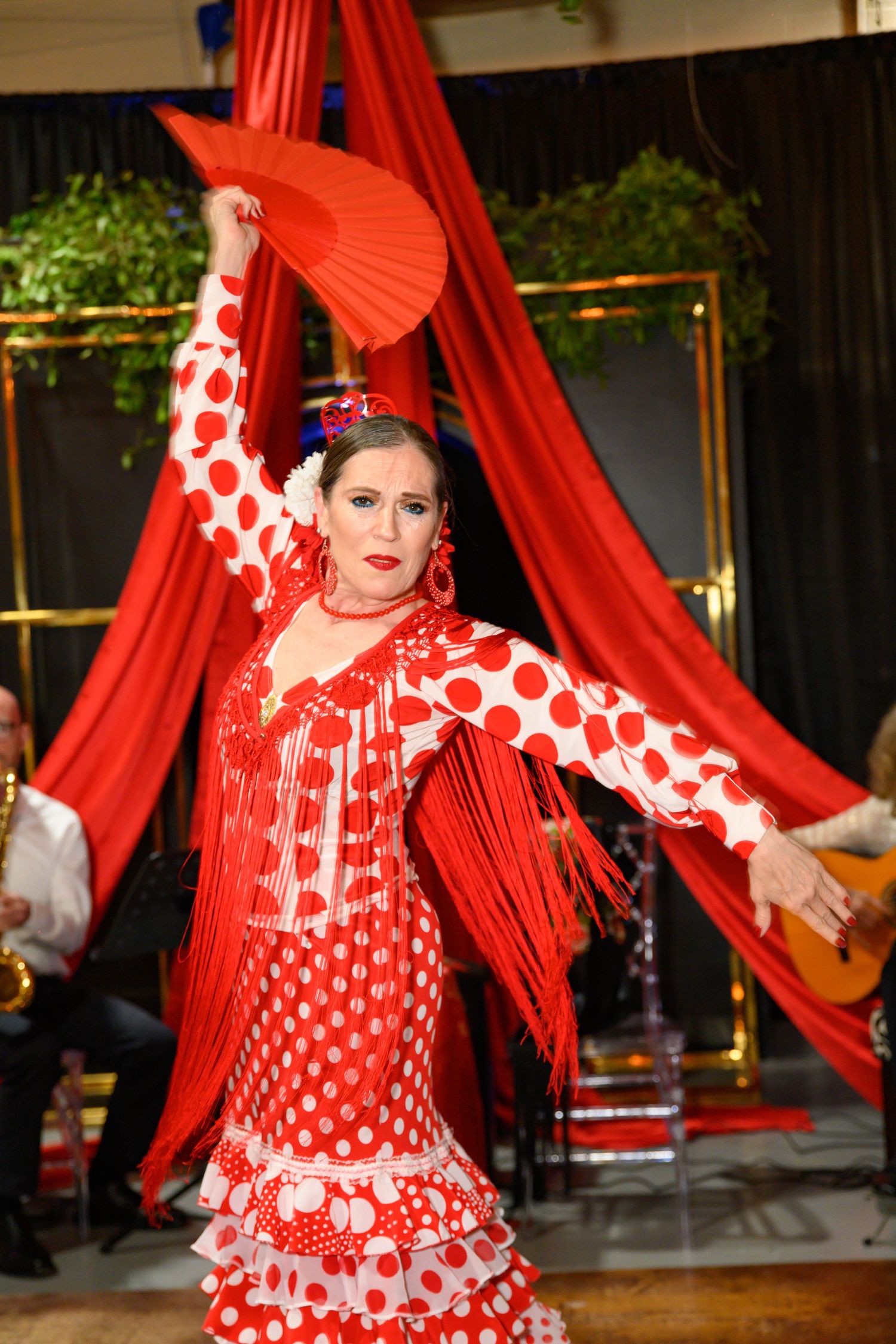 Flamenco dancers in vibrant red and white polka dot dresses perform with flowing fabric during a traditional Spanish dance show.