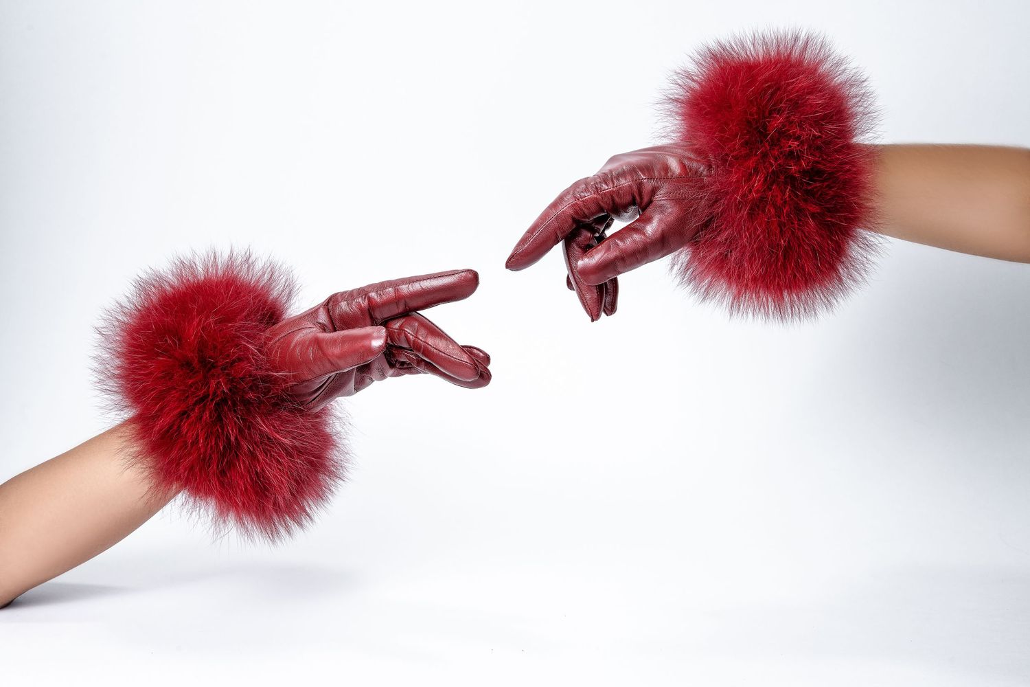 Two hands wearing red furry cuffs reach toward each other against a white background.