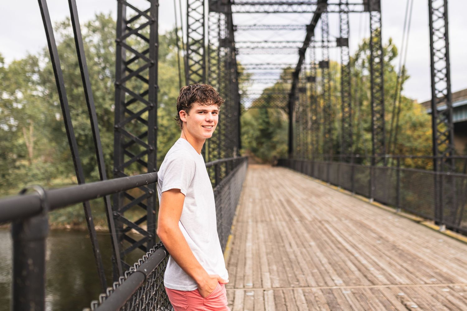 A senior boy posing for senior portraits on an old bridge in Portland, MI